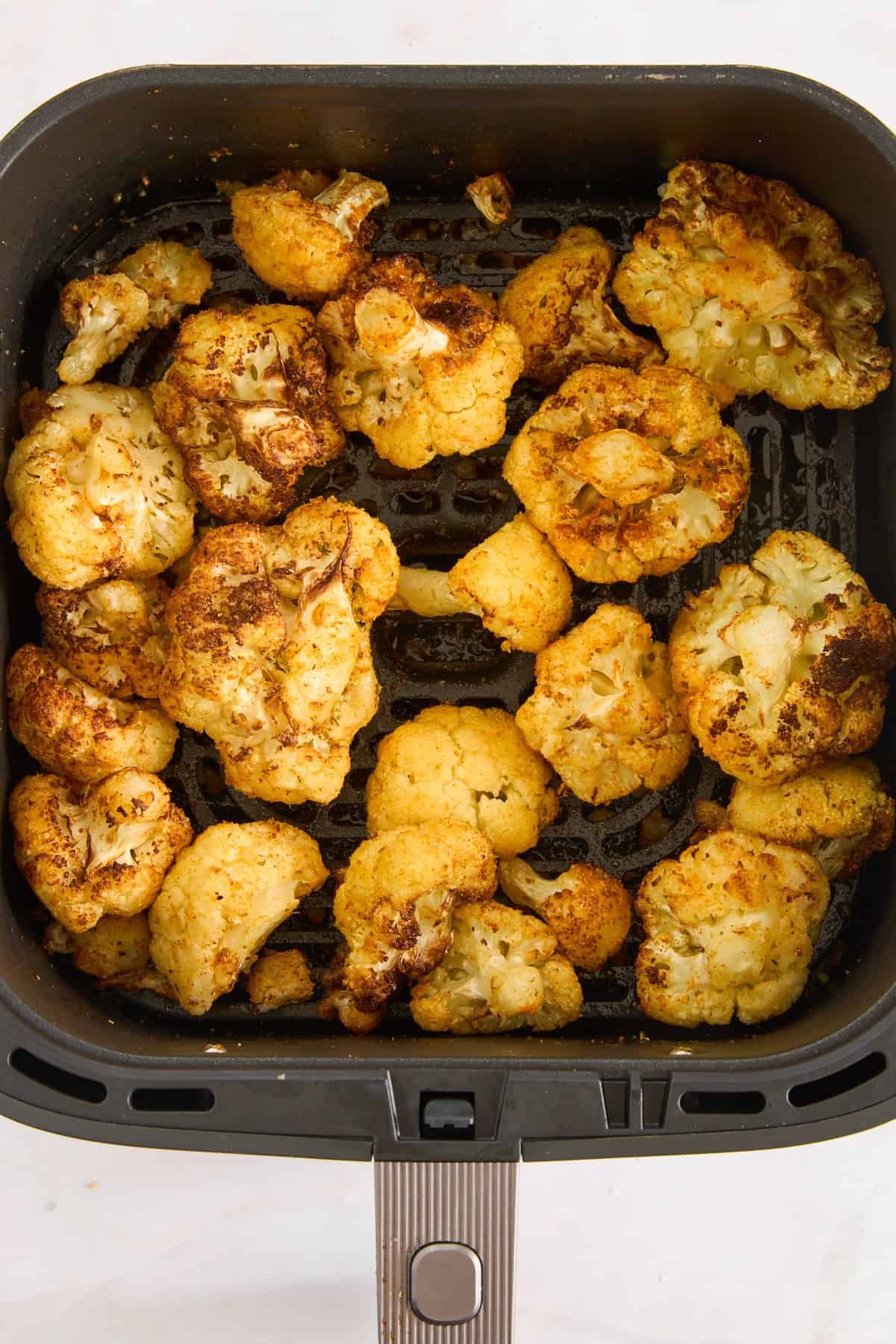 Roasted cauliflower in an air fryer basket.