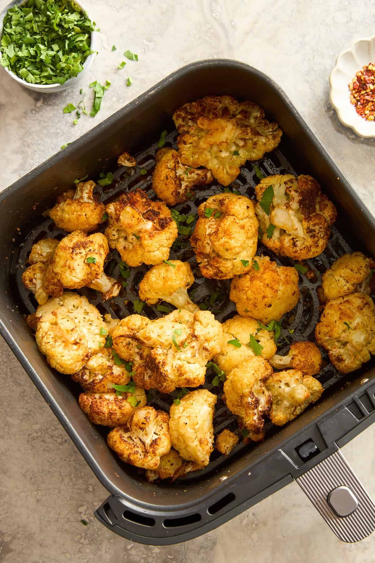 Roasted cauliflower in an air fryer basket.
