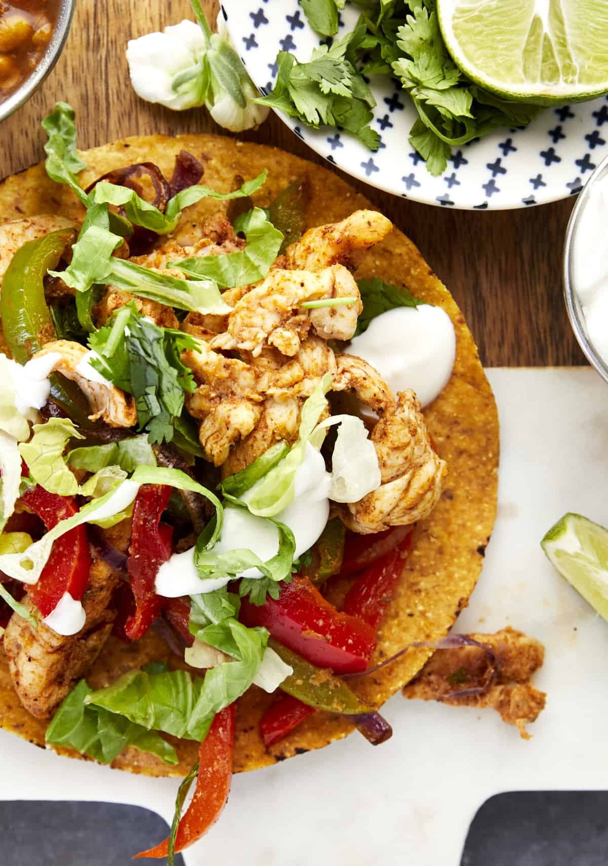 An air fryer chicken fajita taco topped with lettuce, sour cream, and cilantro.