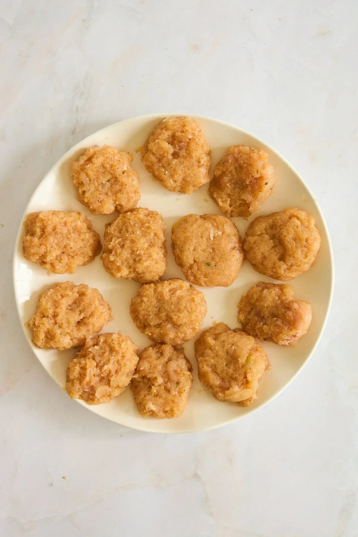 Raw chicken nuggets on a plate.