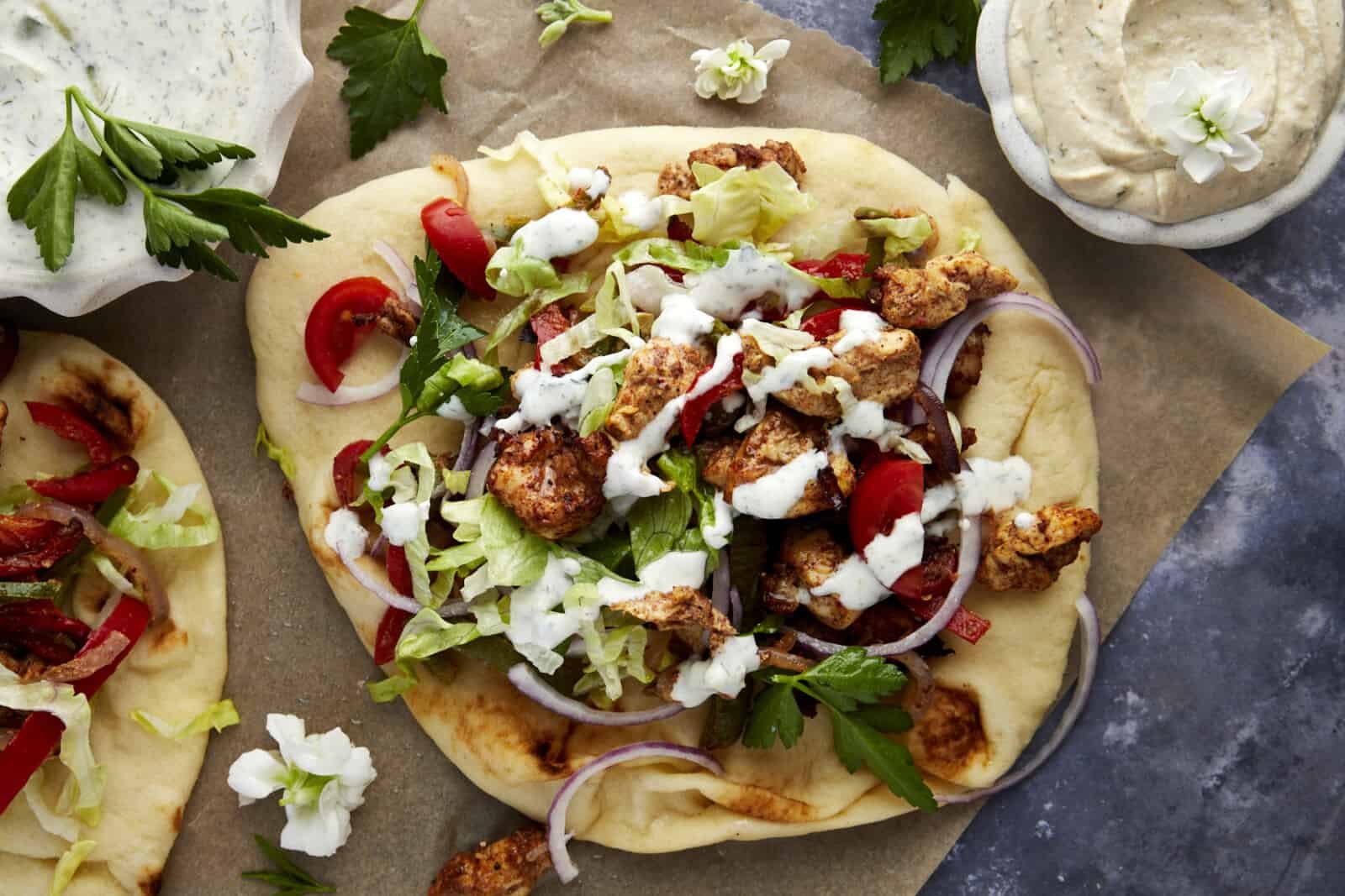 An air fryer chicken shawarma wrap topped with tzatziki sauce.