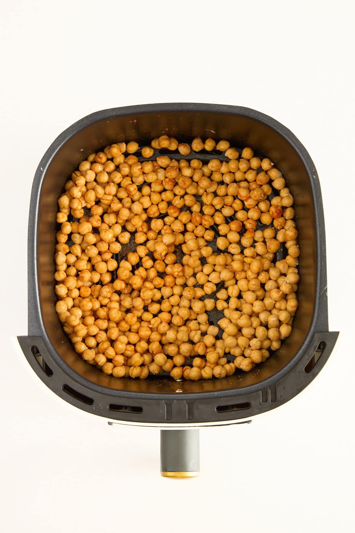 Uncooked chickpeas in an air fryer basket.
