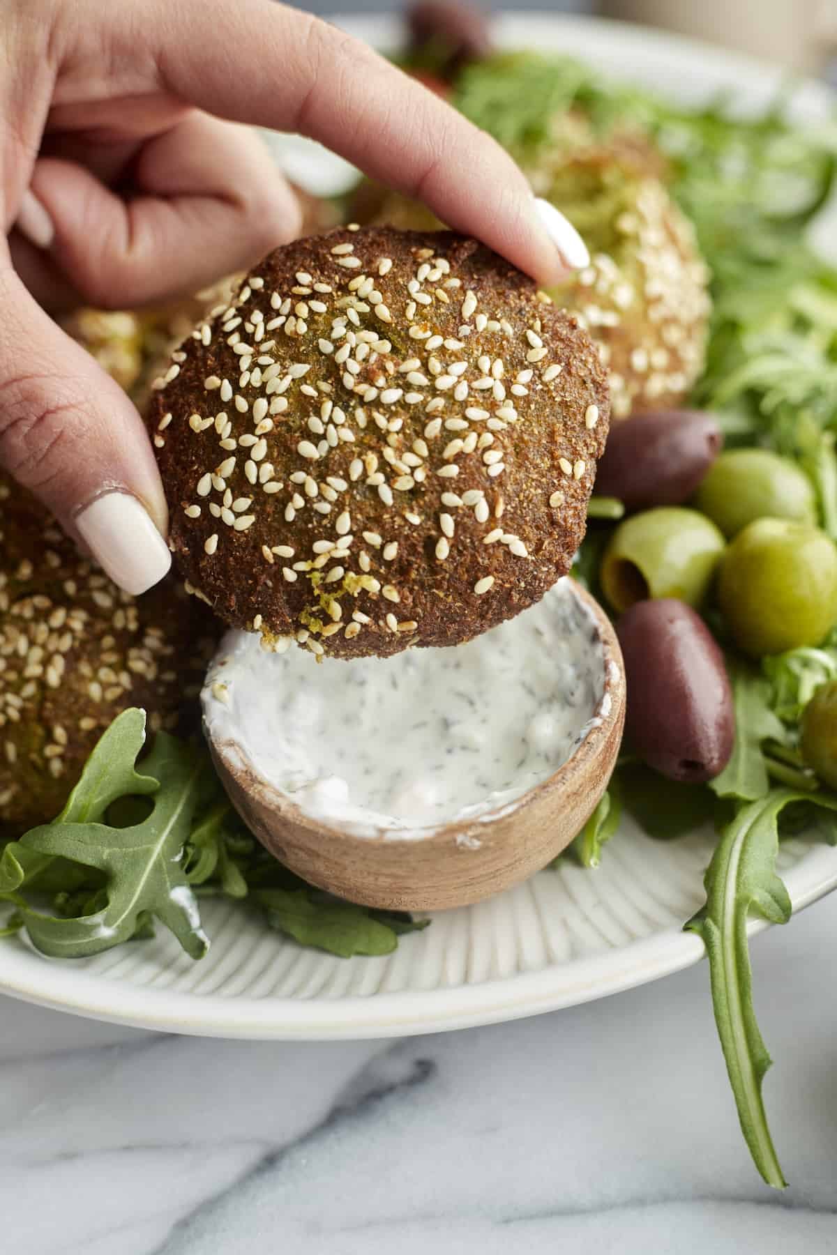 close up image of an air fryer falafel topped with sesame seeds.