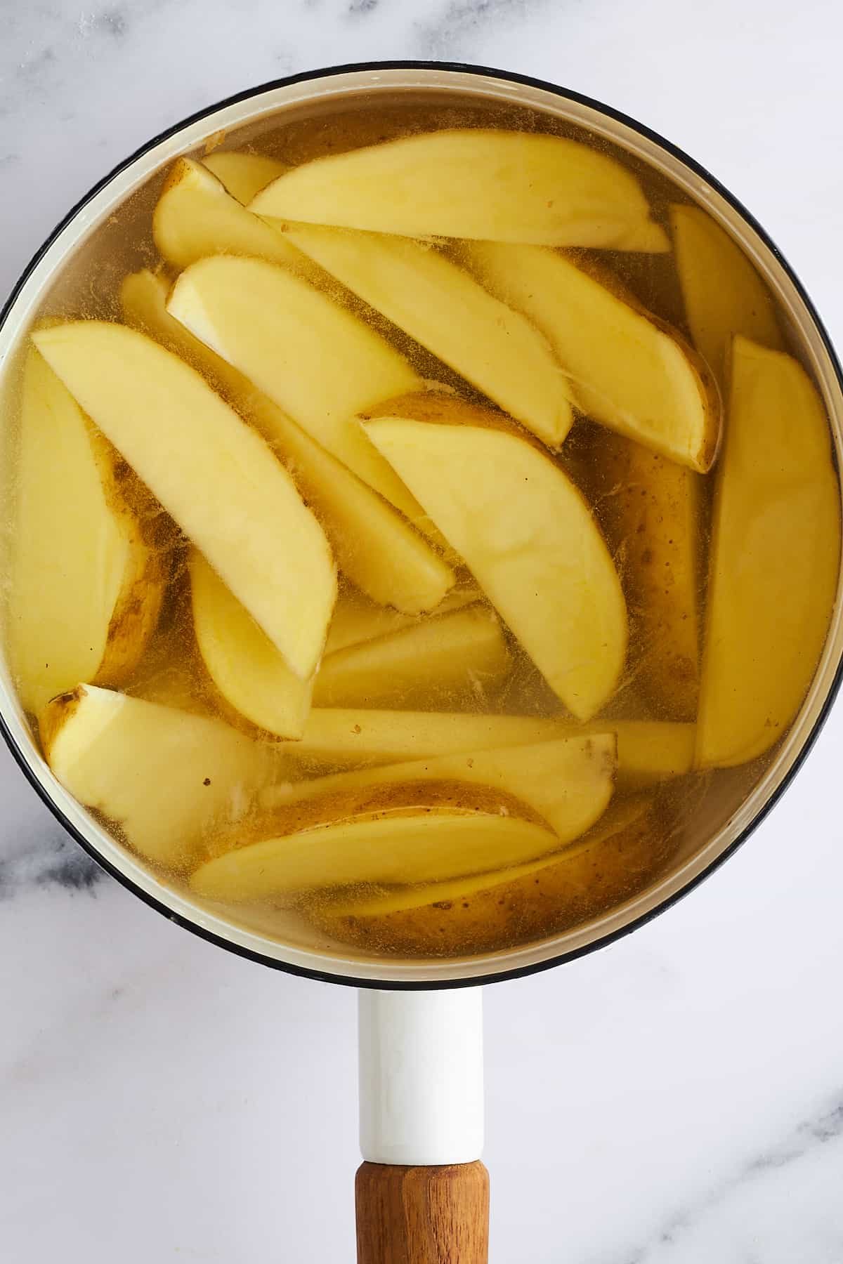 Potato wedges in a pot of water.