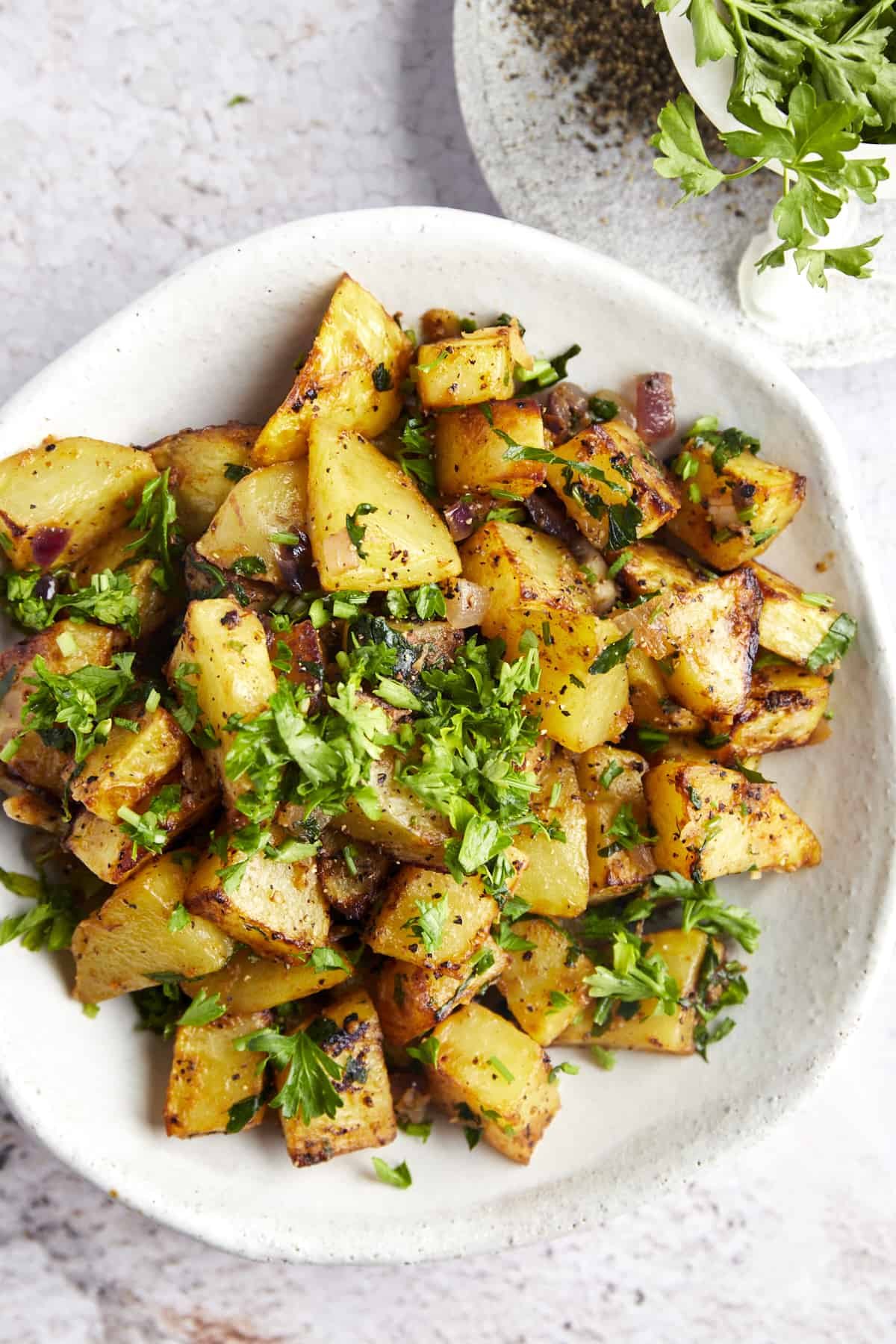 Overhead image of a plate of air fryer golden potatoes tossed in harissa sauce.