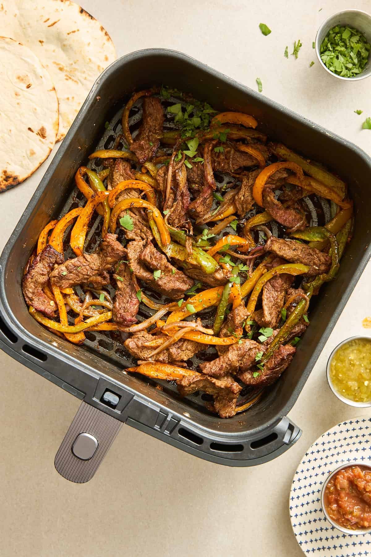 An air fryer basket full of steak fajitas.
