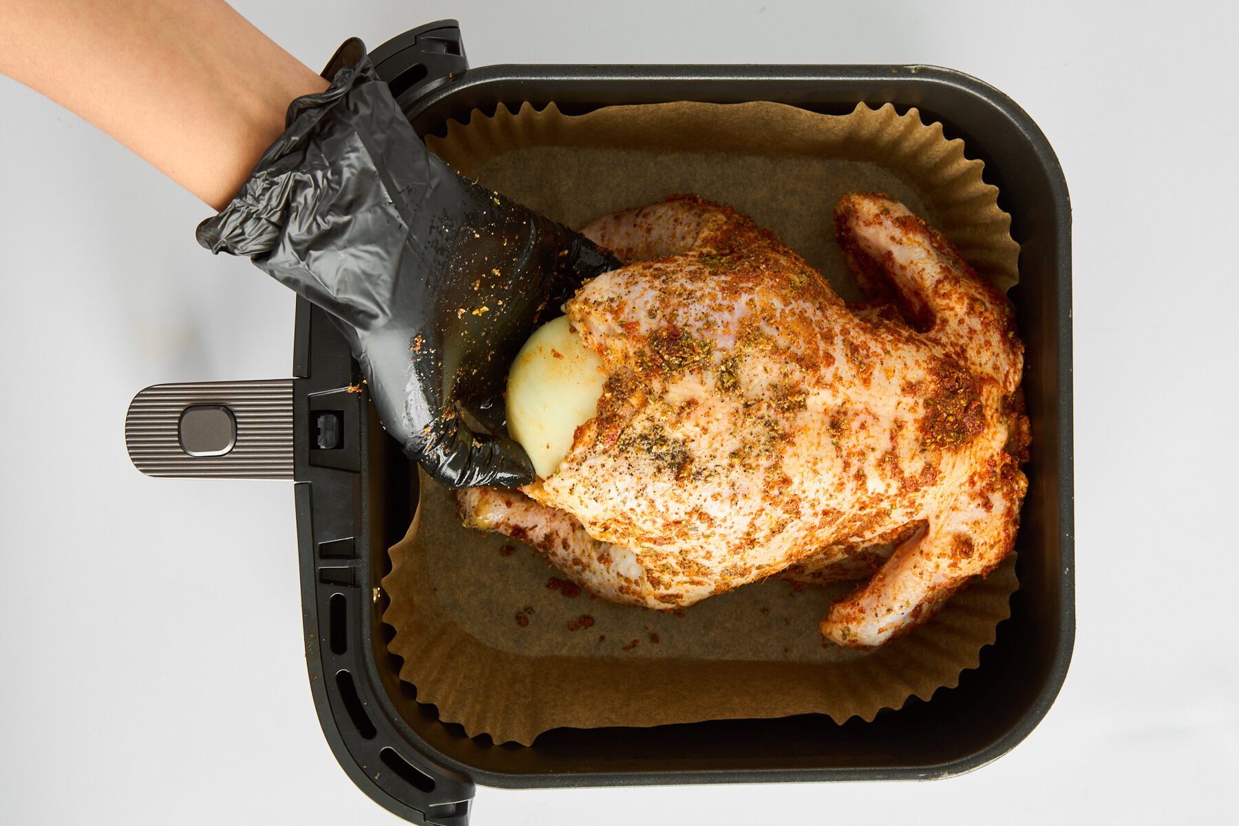 A hand stuffing a raw chicken.