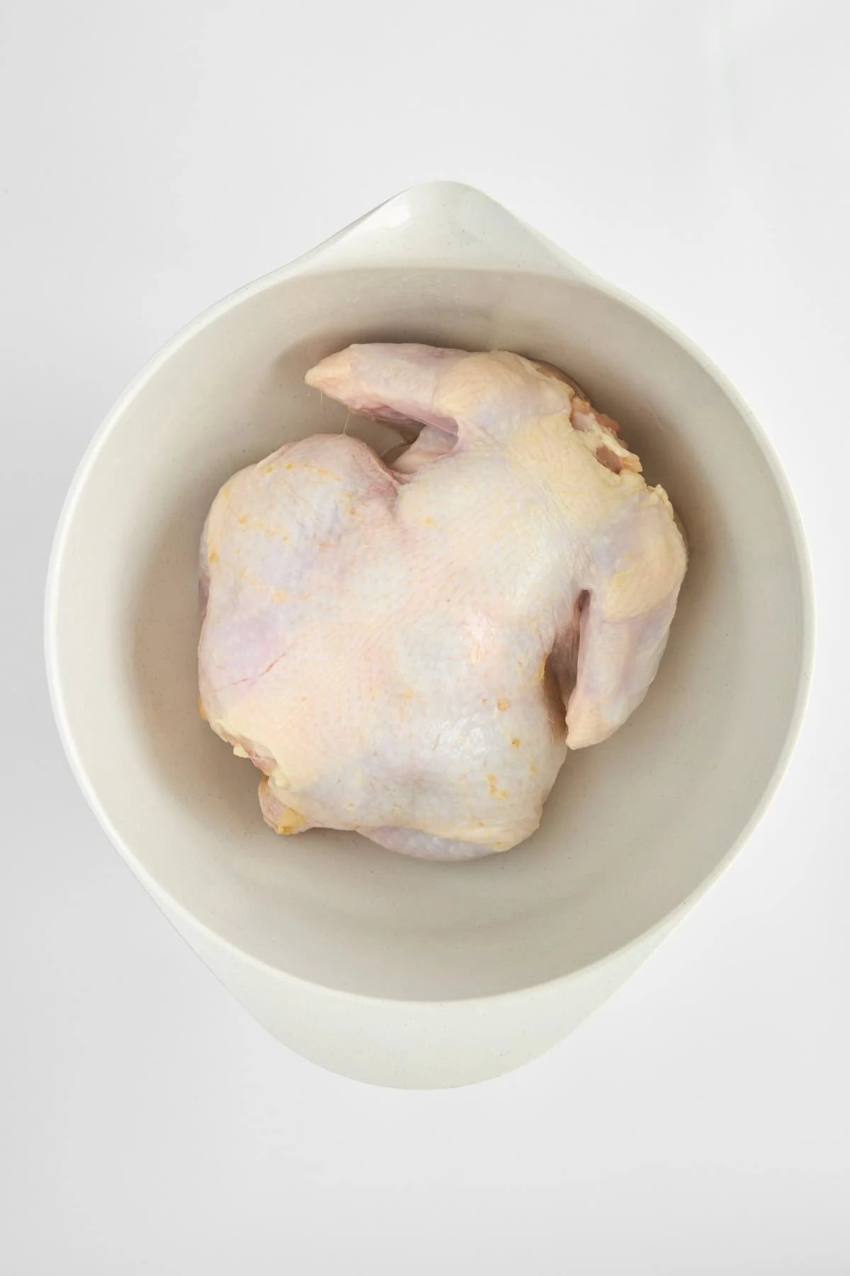 A raw whole chicken in a bowl.