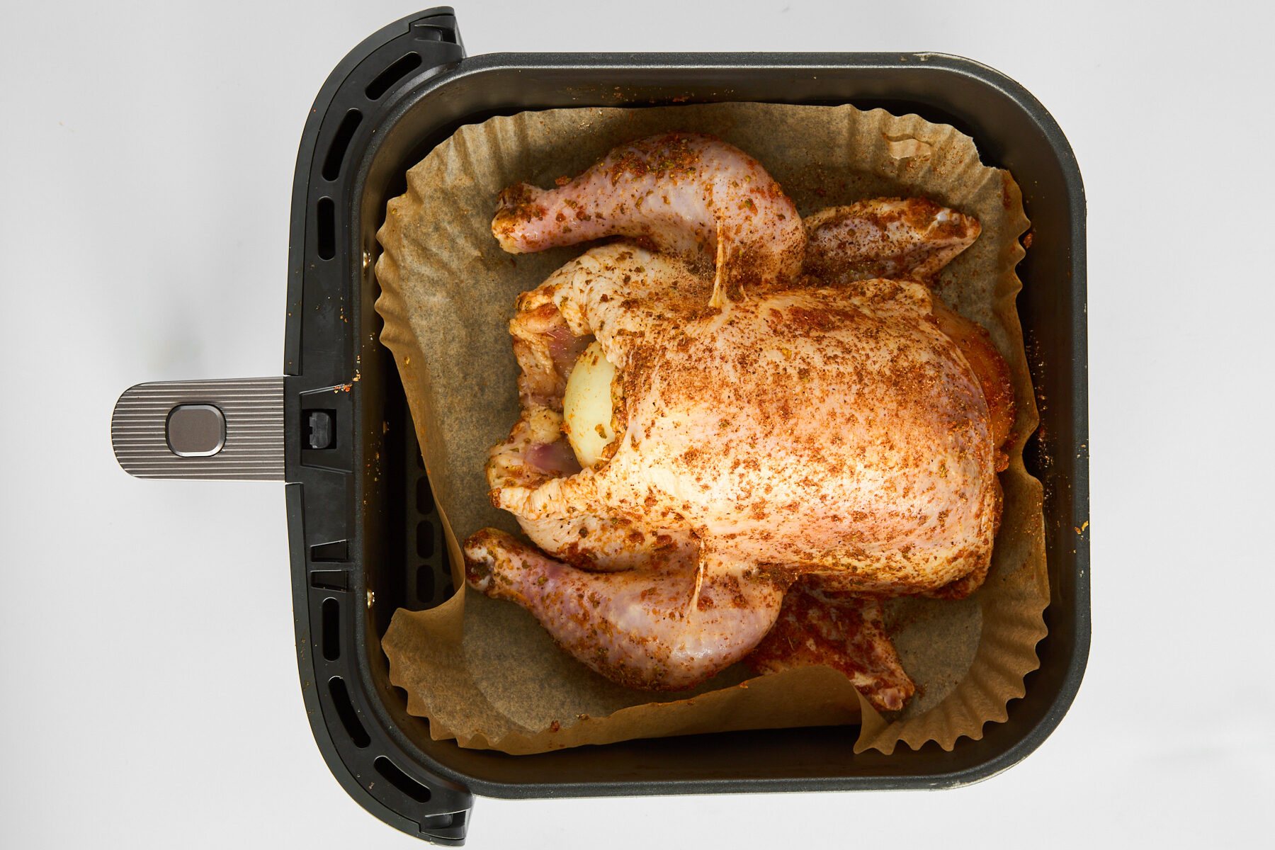 A raw whole chicken in an air fryer.