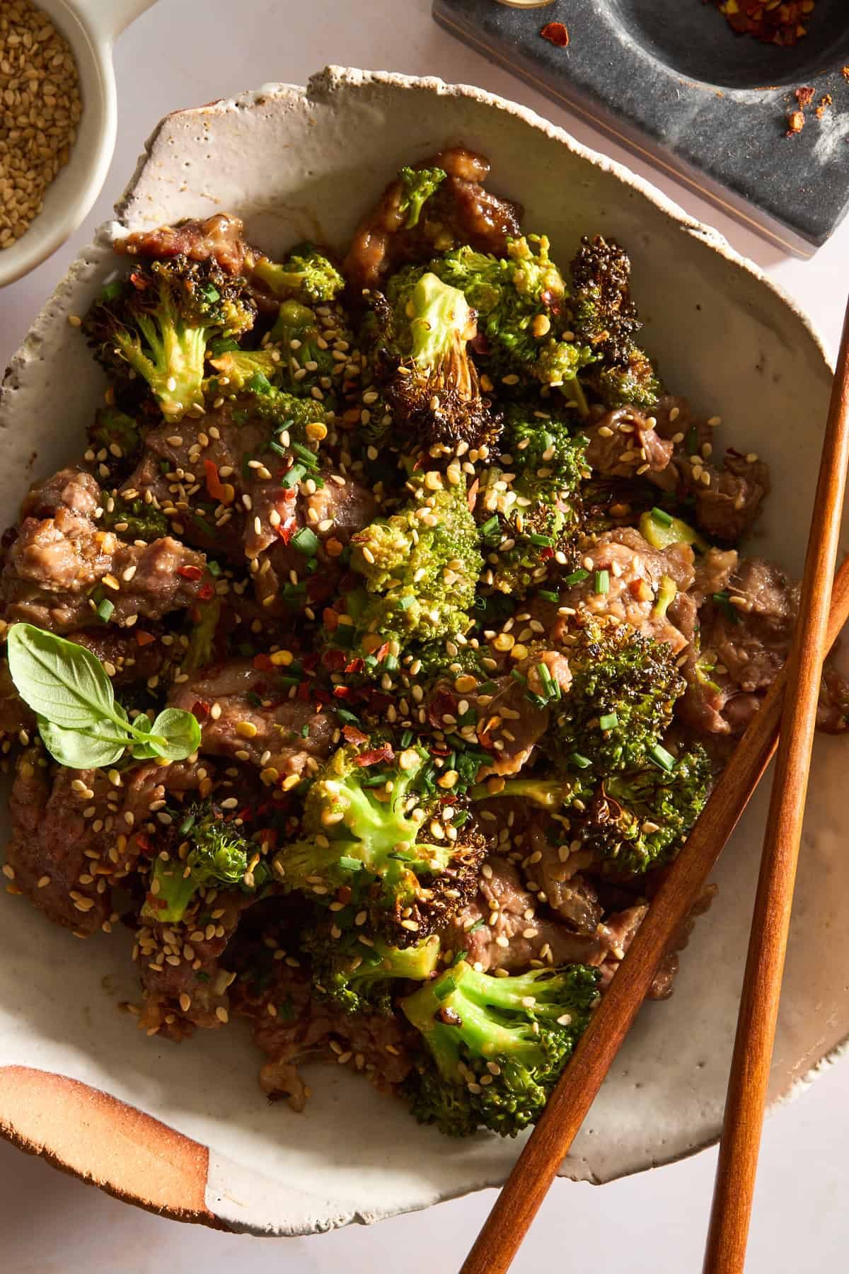 A bowl of air fryer beef and broccoli with chopsticks balanced on the side.