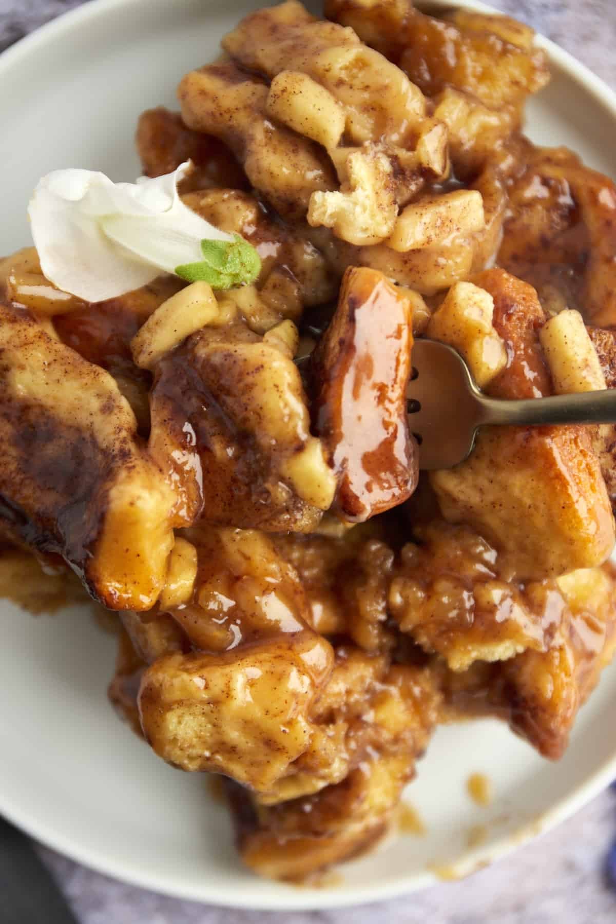 close up image of a plate full of cinnamon rolls with a fork stabbing a bite
