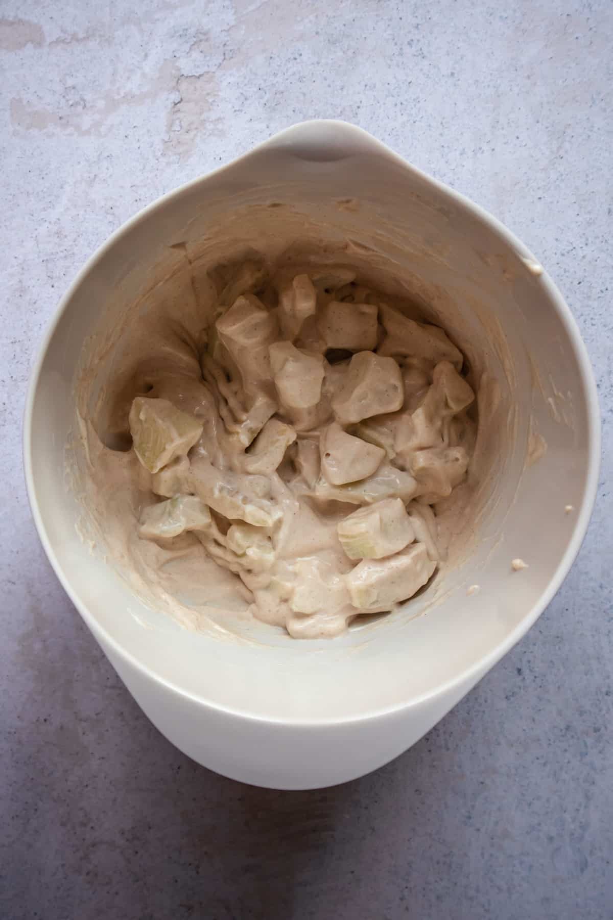 apples tossed with a cream cheese cinnamon mixture in a bowl