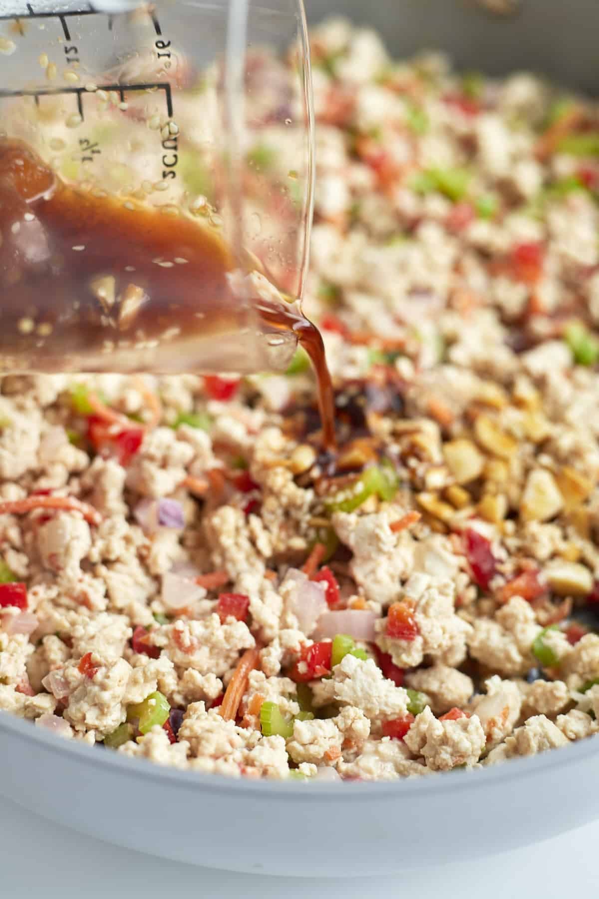 asian chicken and veggies being stirred in a skillet.