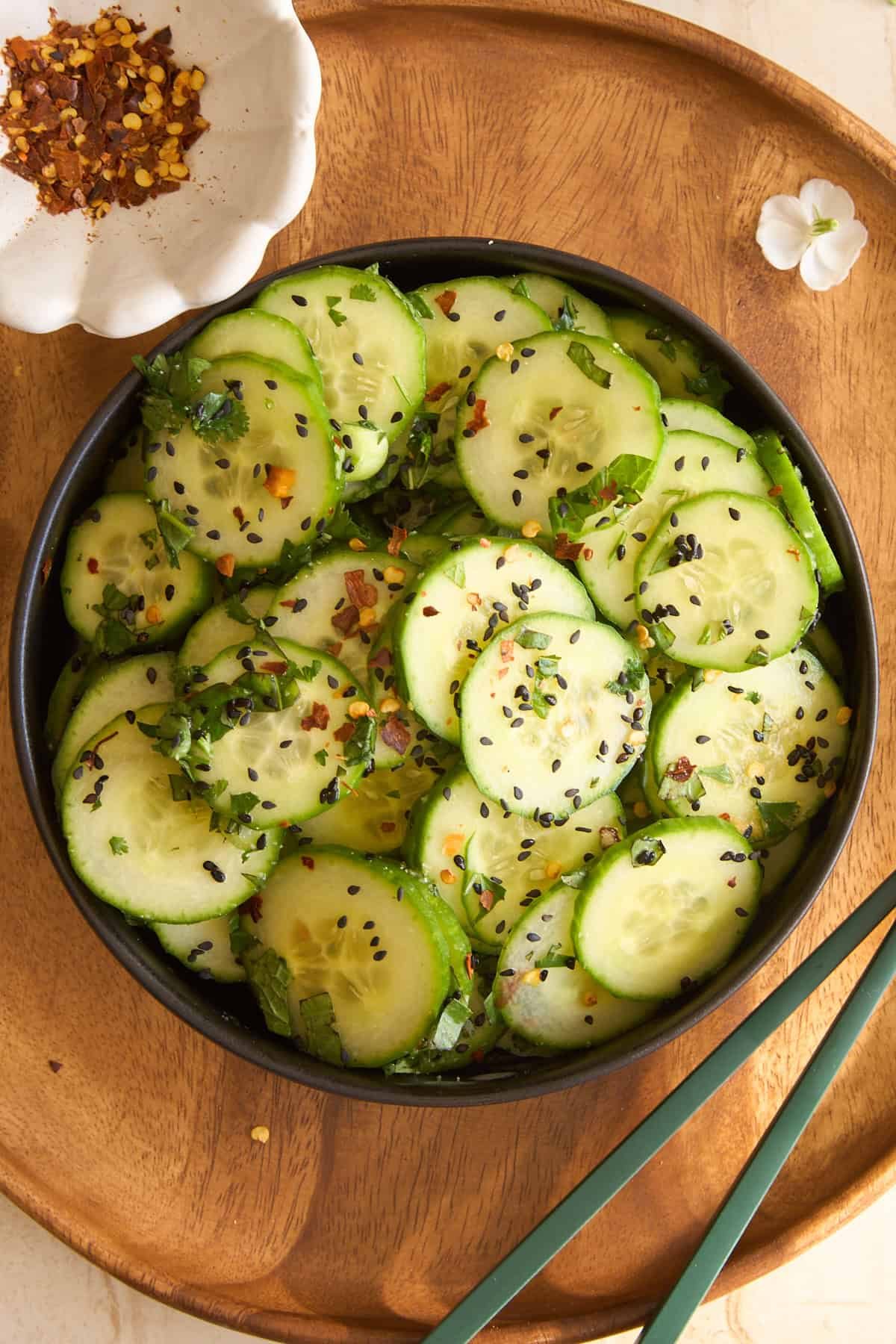 Asian cucumber salad in a bowl next to chopsticks