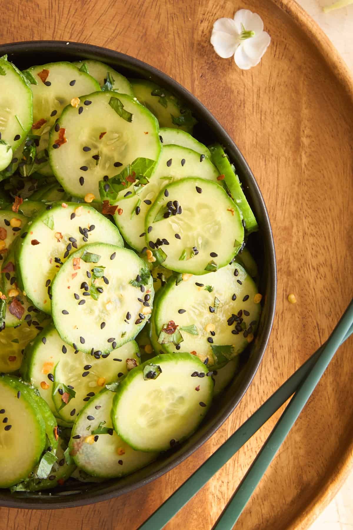Asian cucumber salad in a bowl next to chopsticks
