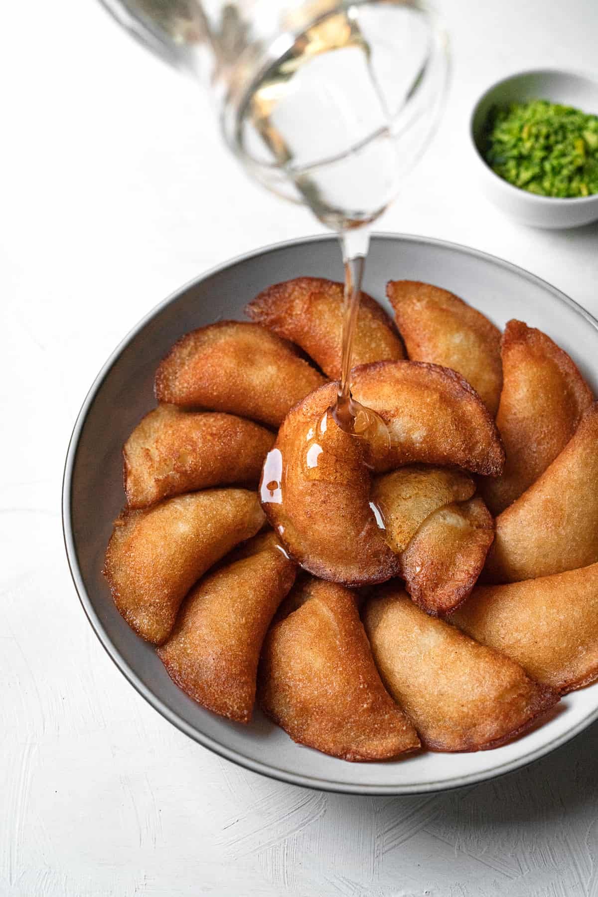 simple syrup being poured on atayef on platter