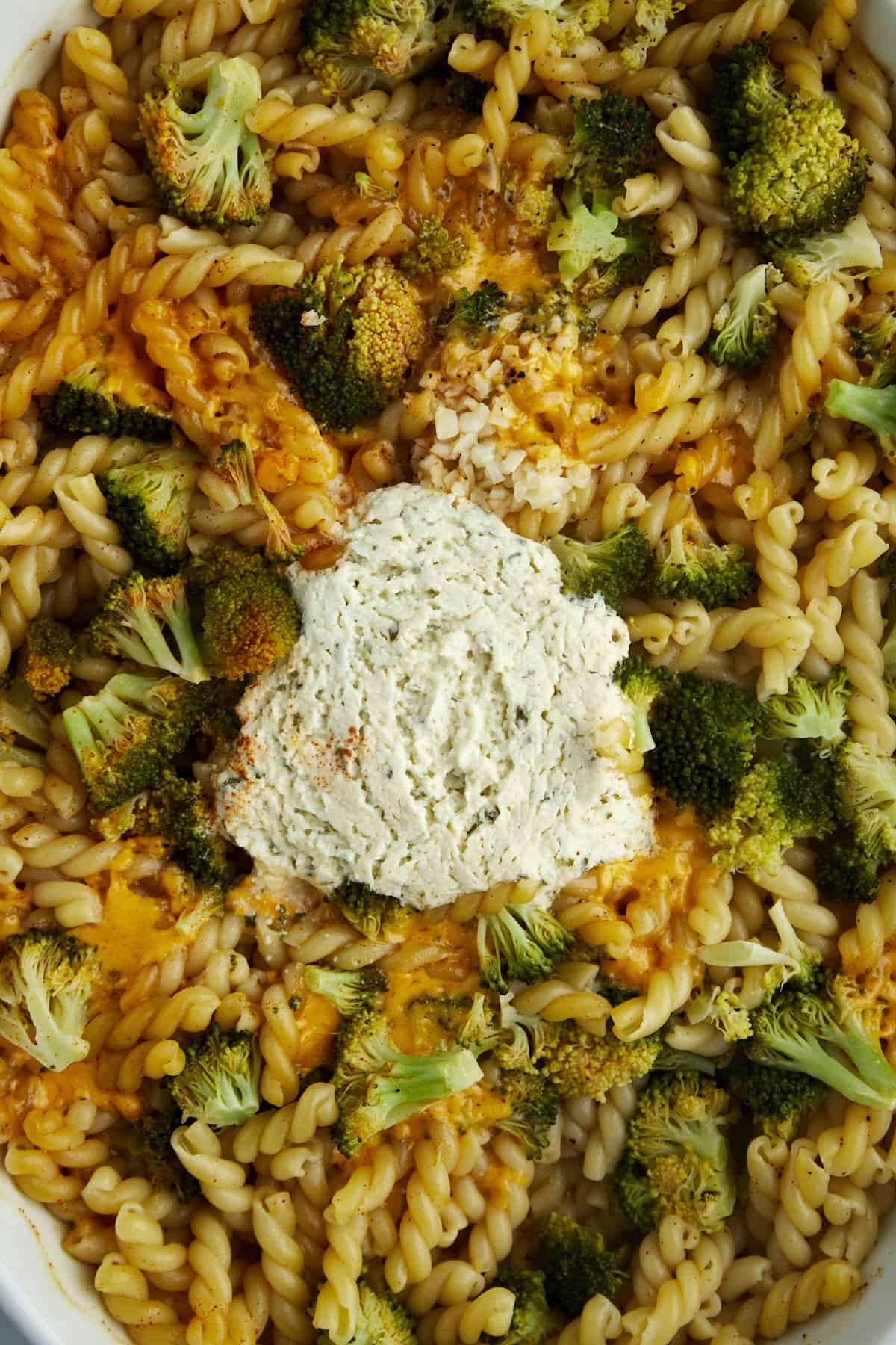 Overhead image of a baking dish with noodles, Boursin, broccoli, cheddar, and seasonings.