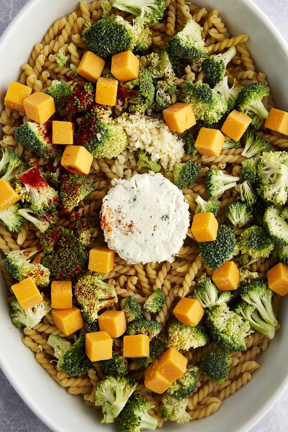 Overhead image of a baking dish with noodles, Boursin, broccoli, cheddar, and seasonings.
