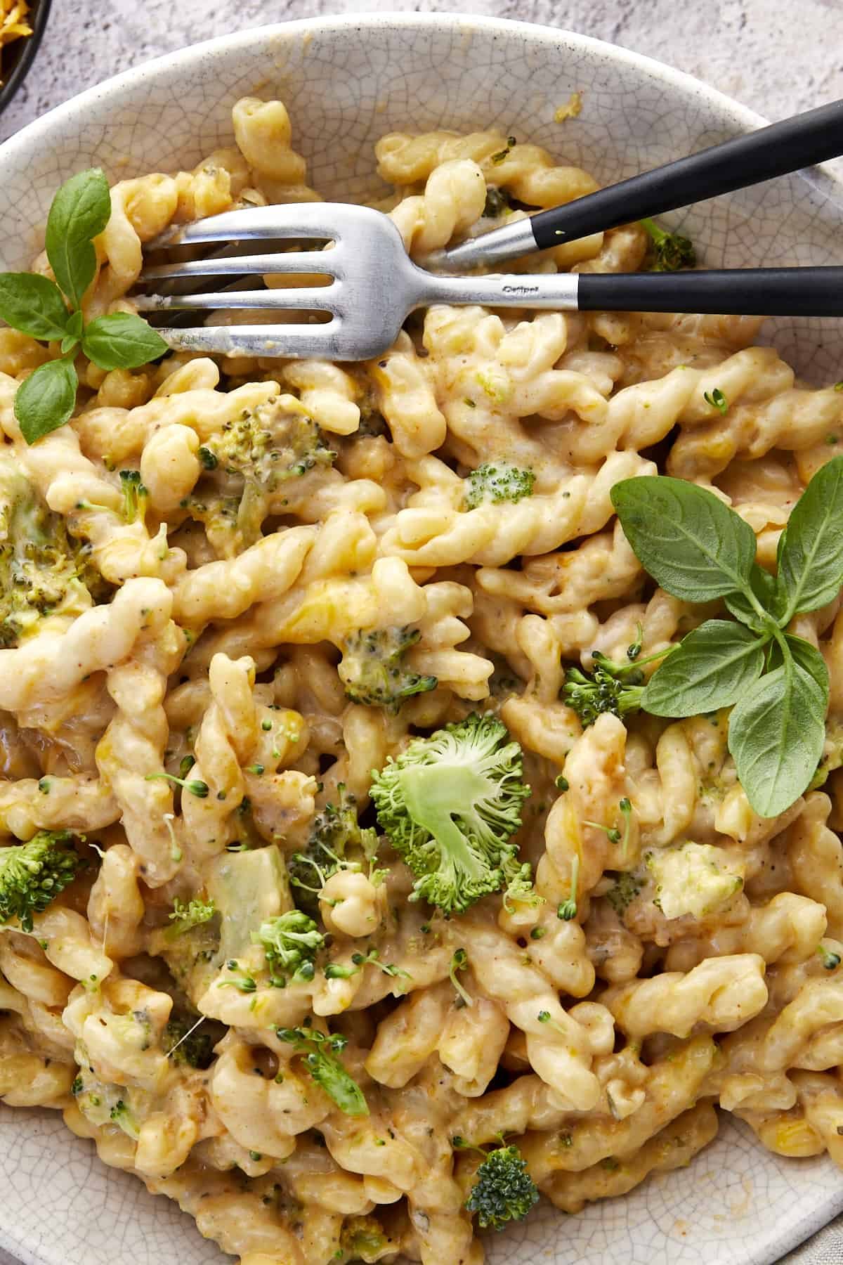 Two forks on the side of a bowl of baked broccoli mac and cheese.
