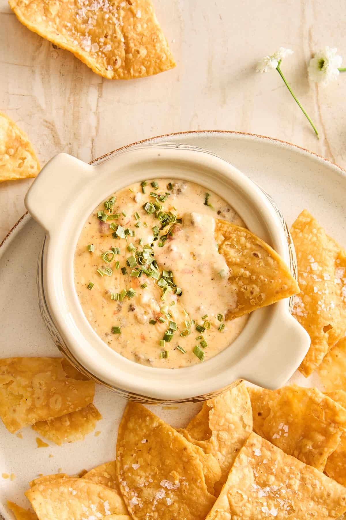 a chip being dipped into baked queso dip