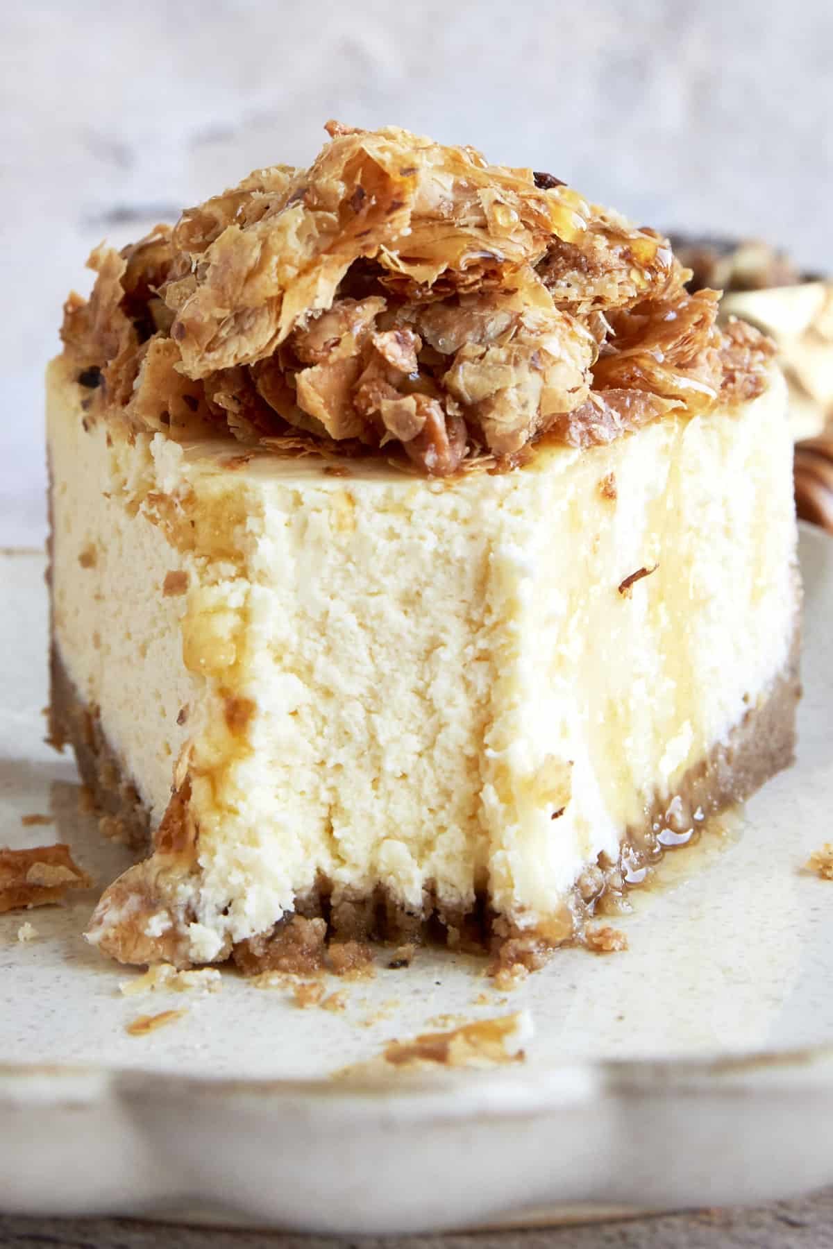 Front view of a slice of baklava cheesecake with a bite taken from the tip.