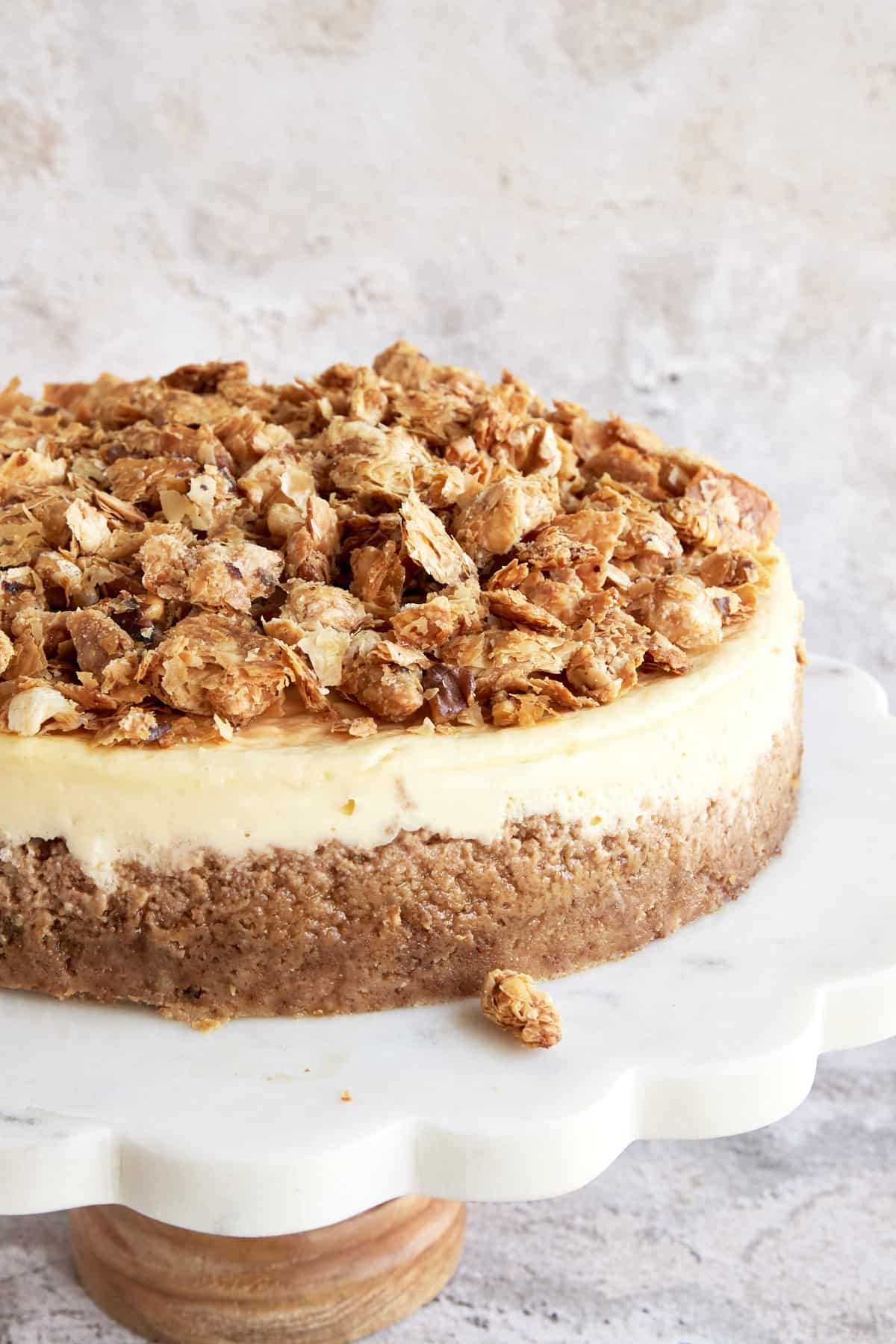 A baklava cheesecake on a white cake stand.