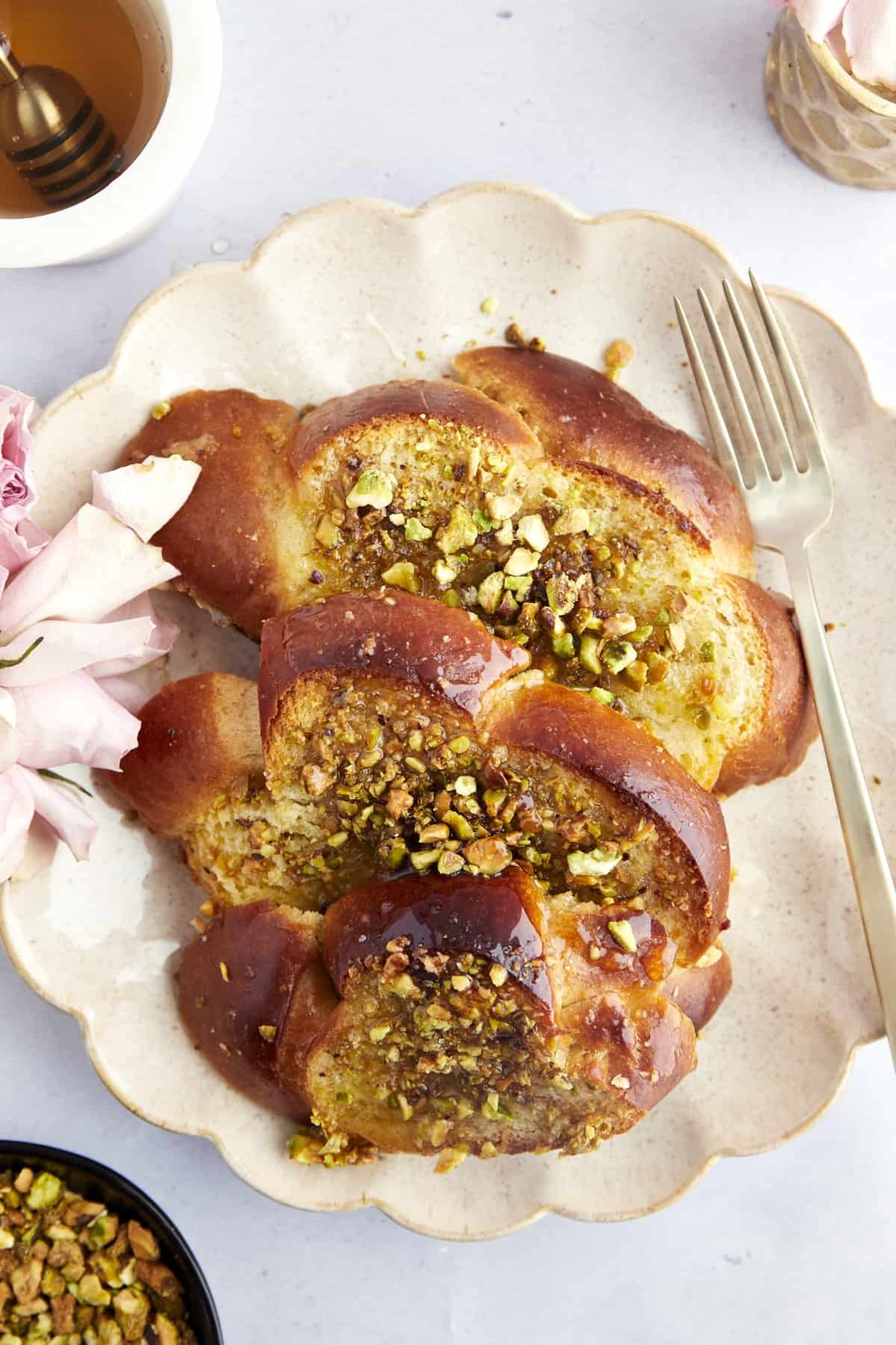 Three pieces of Baklava French toast on a plate topped with syrup with a fork on the side.