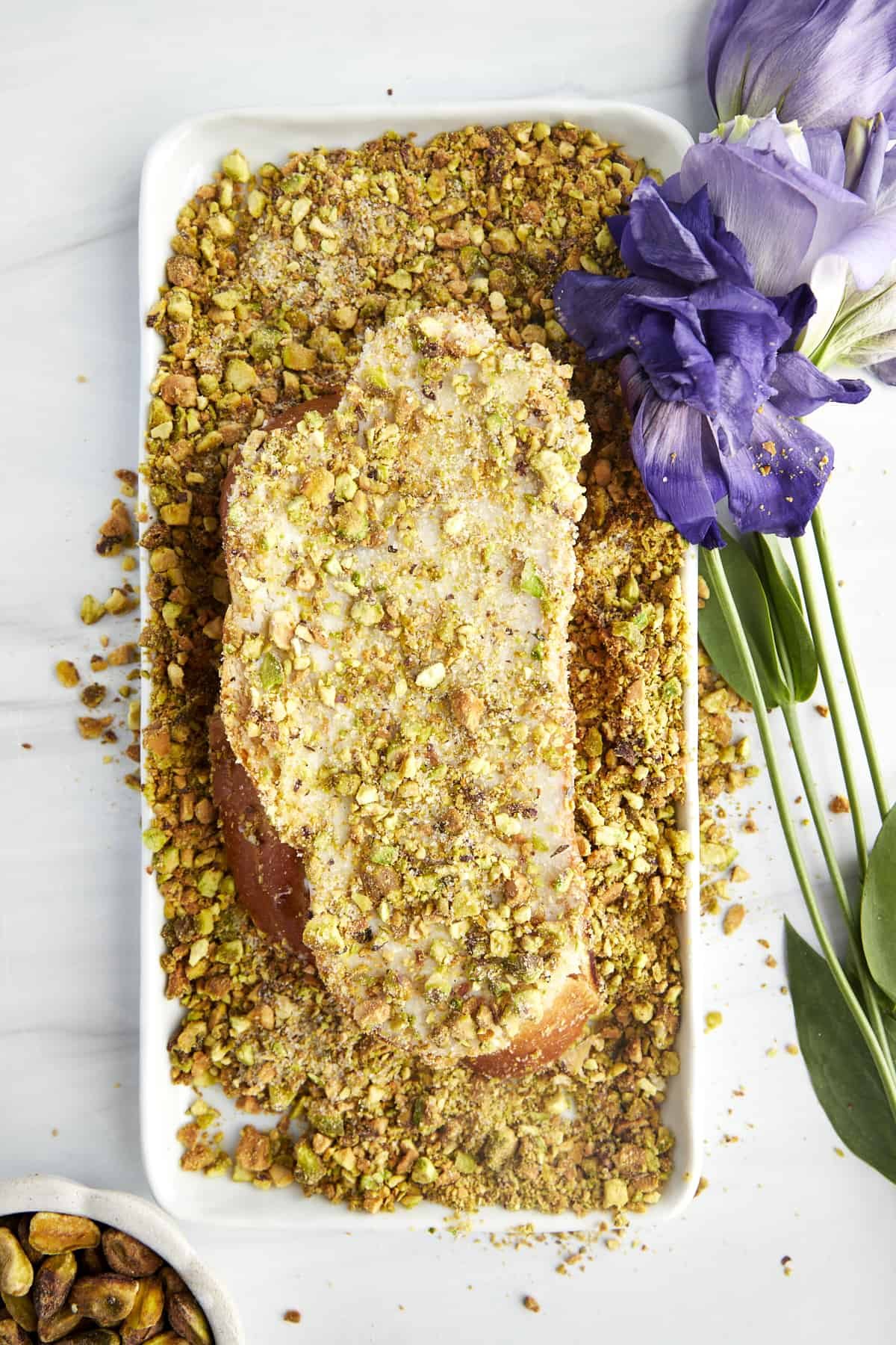 A slices of baklava french toast coated with a sugared pistachio mixture.