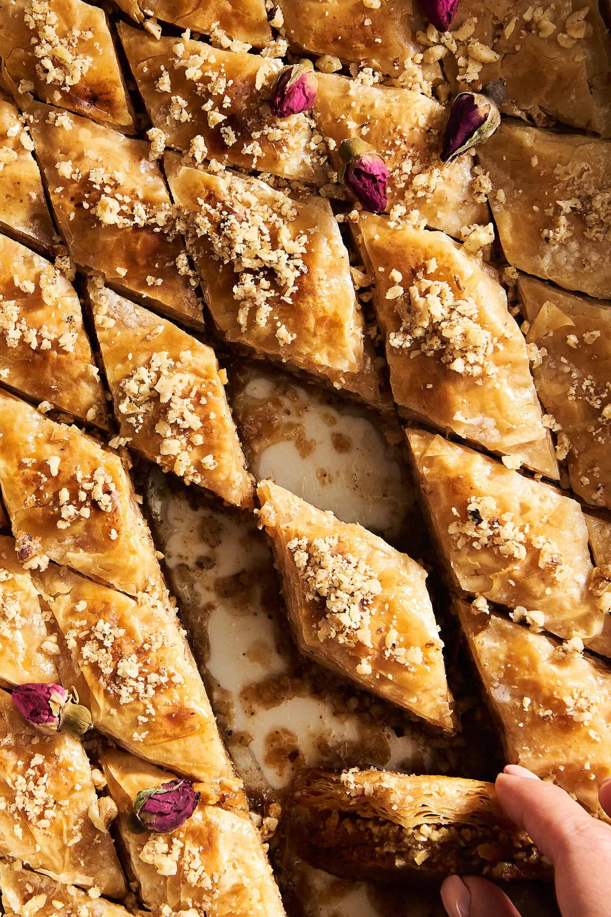 A baking dish of baklava pieces with a few pieces missing.