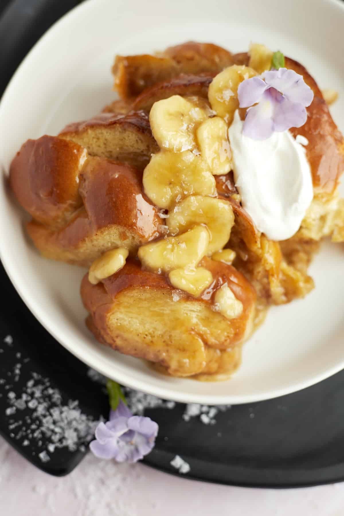 bananas foster french toast on a plate topped with banana slices and creme fraiche
