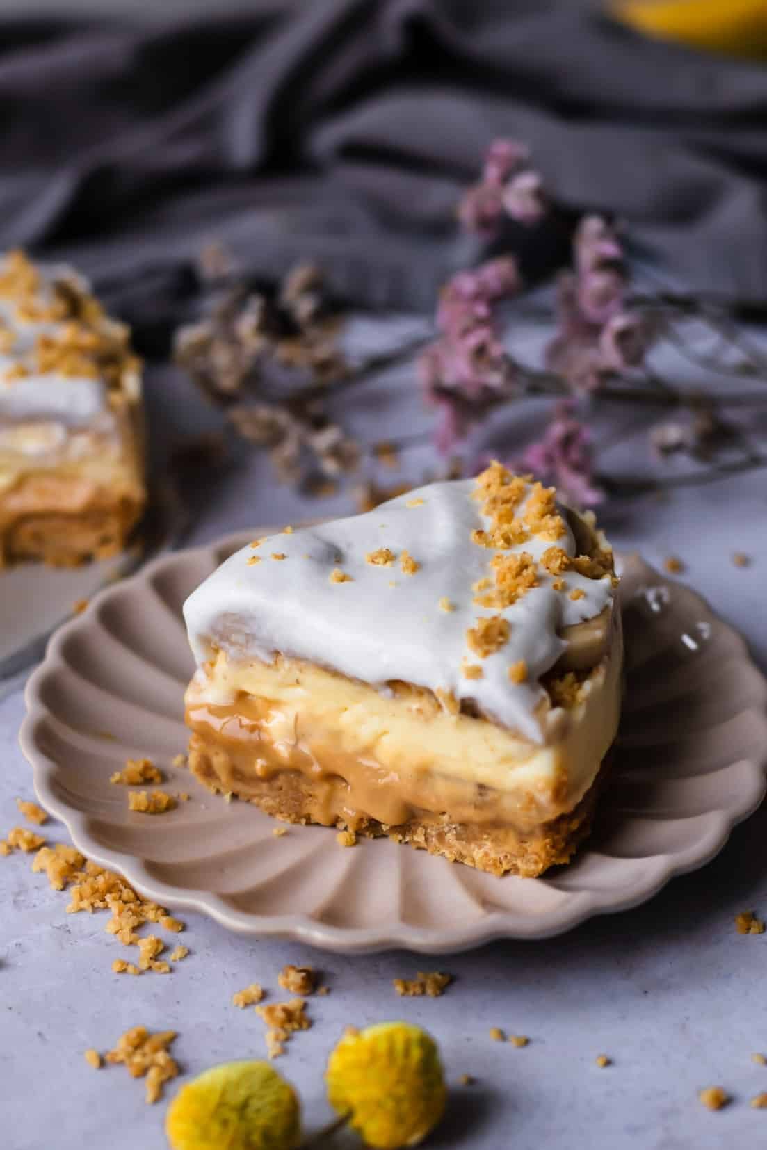 a piece of banoffee pie on a beige plate topped with a sprinkle of graham cracker crumbs