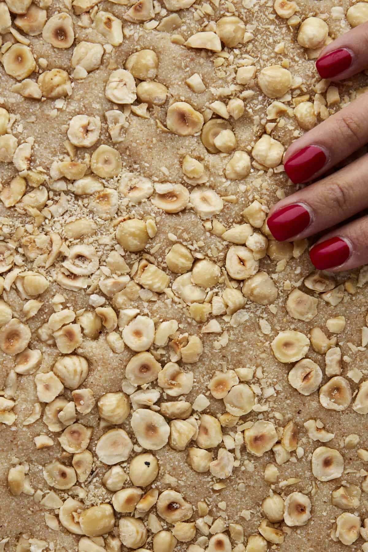 Hazelnuts being pressed into chilled, unbaked basbousa batter.