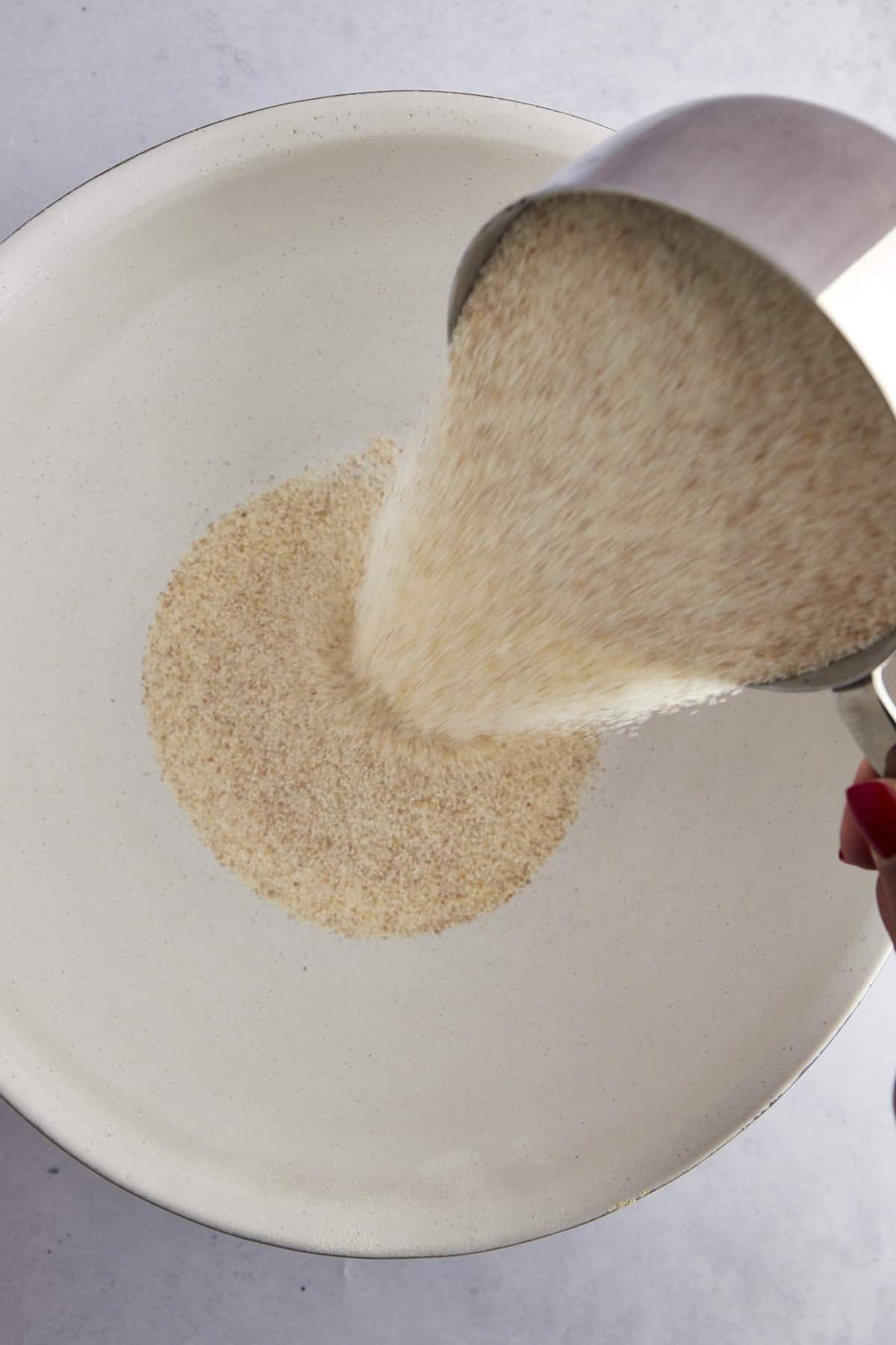Semolina flour being poured into a bowl.