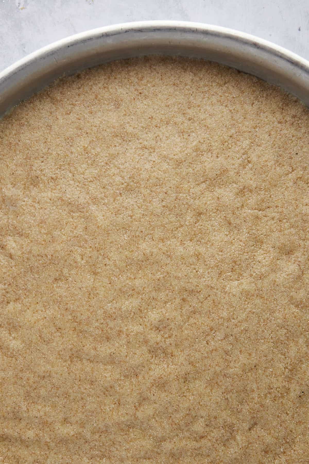 Unbaked basbousa in a round baking pan.