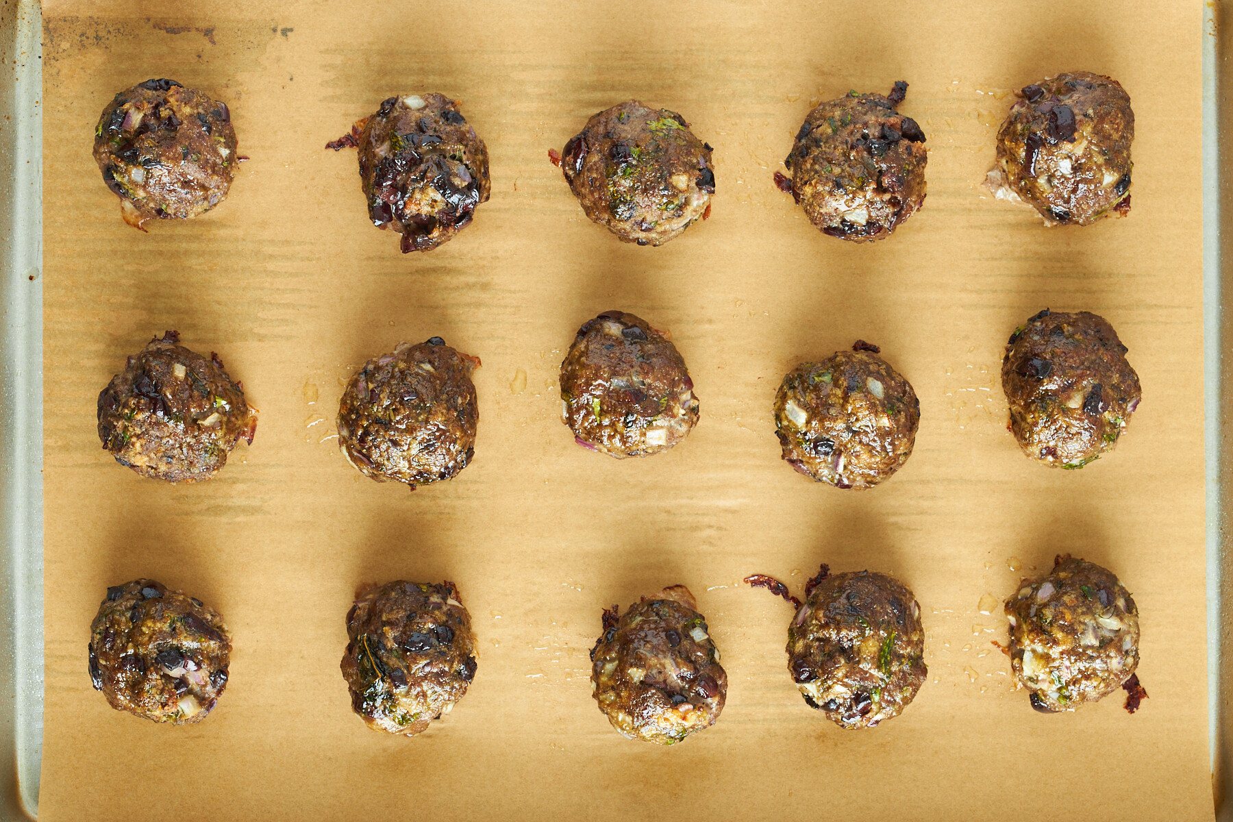 Baked Mediterranean beef meatballs on a baking sheet.