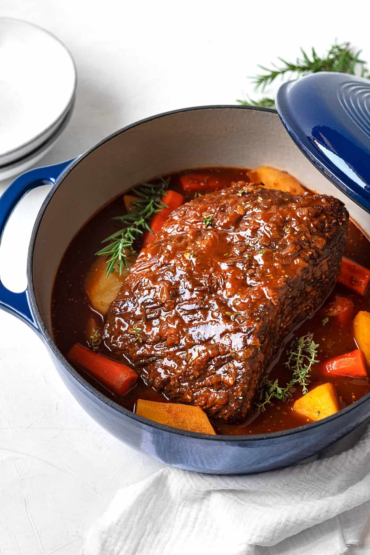 fully cooked beef pot roast in a dutch oven with potatoes and carrots.