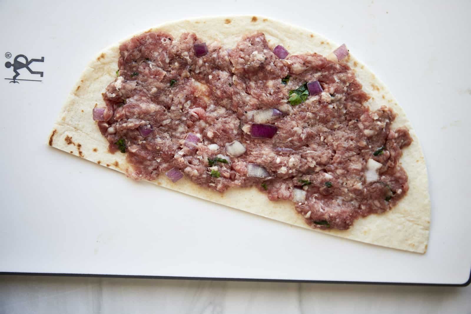 Ground beef spread over a tortilla half.
