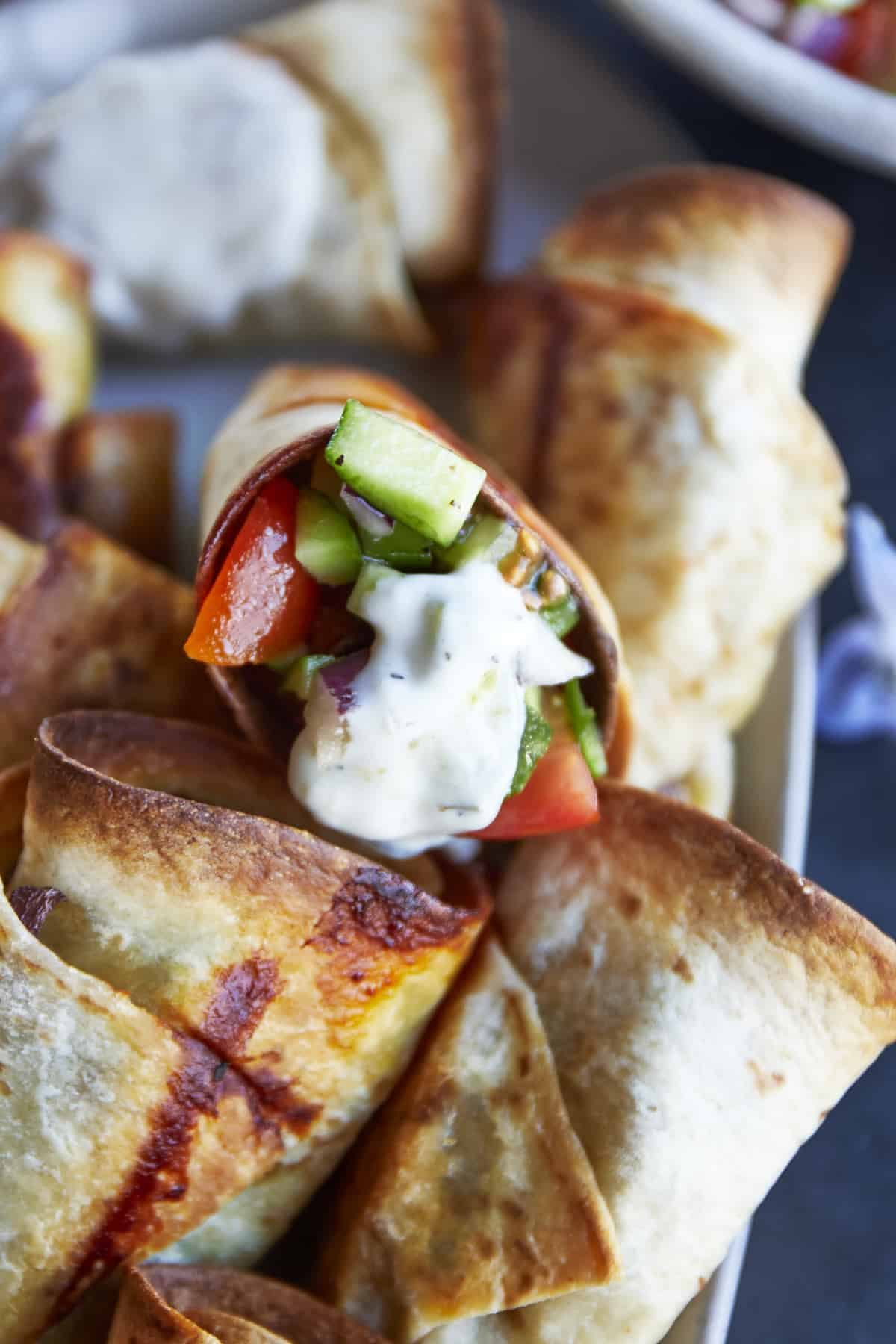 A beef roll with cucumber and tomato salad and tzatziki.