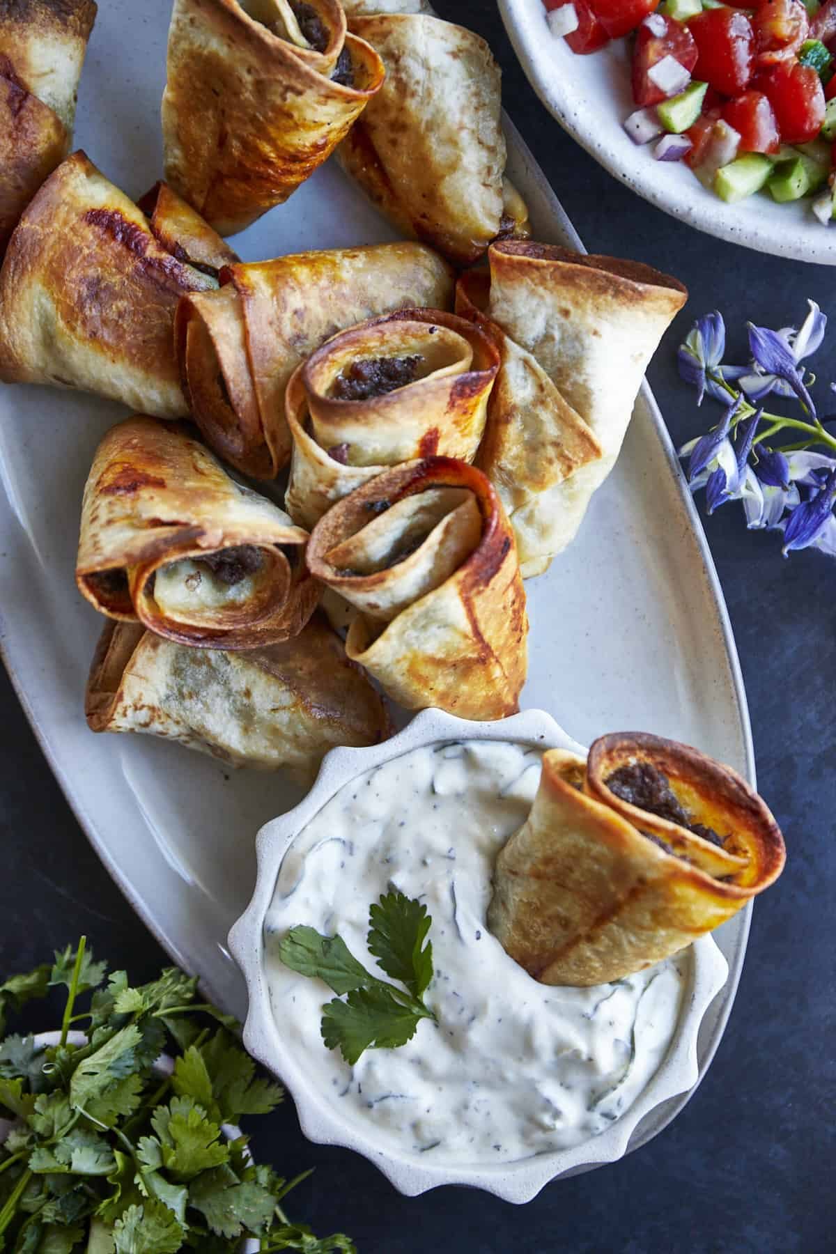 A platter of beef rolls with a side of tzatziki.
