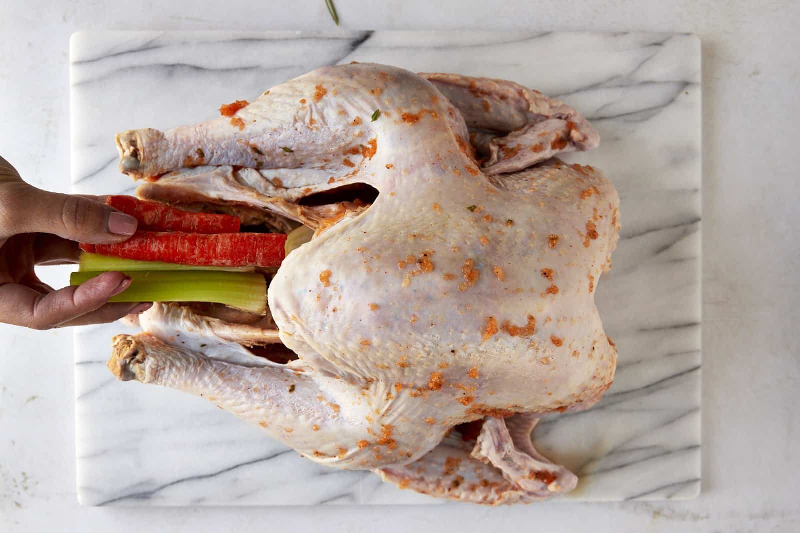 Celery and carrot sticks being placed inside a turkey.