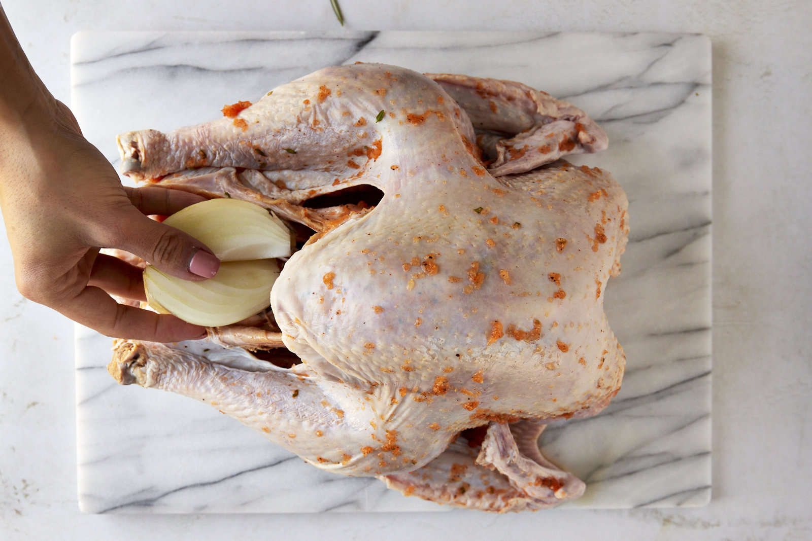A turkey cavity being stuffed with aromatics.