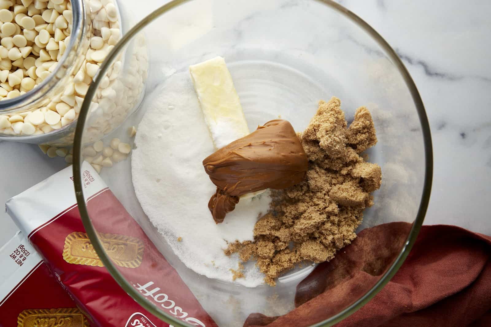 Butter, white sugar, brown sugar, and Biscoff cookie butter in a bowl.