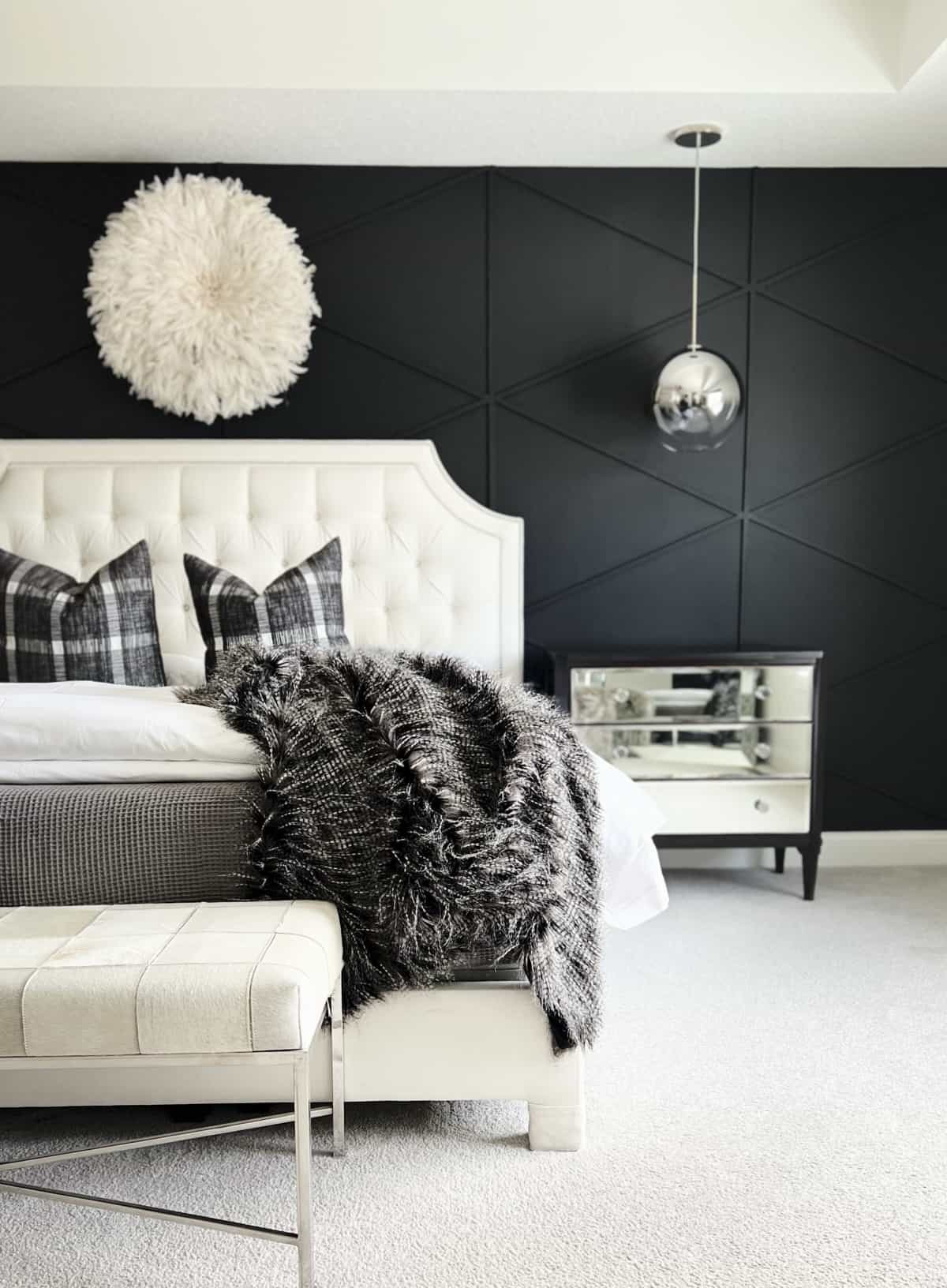 A black accent wall with wood plank diamonds in a bedroom.