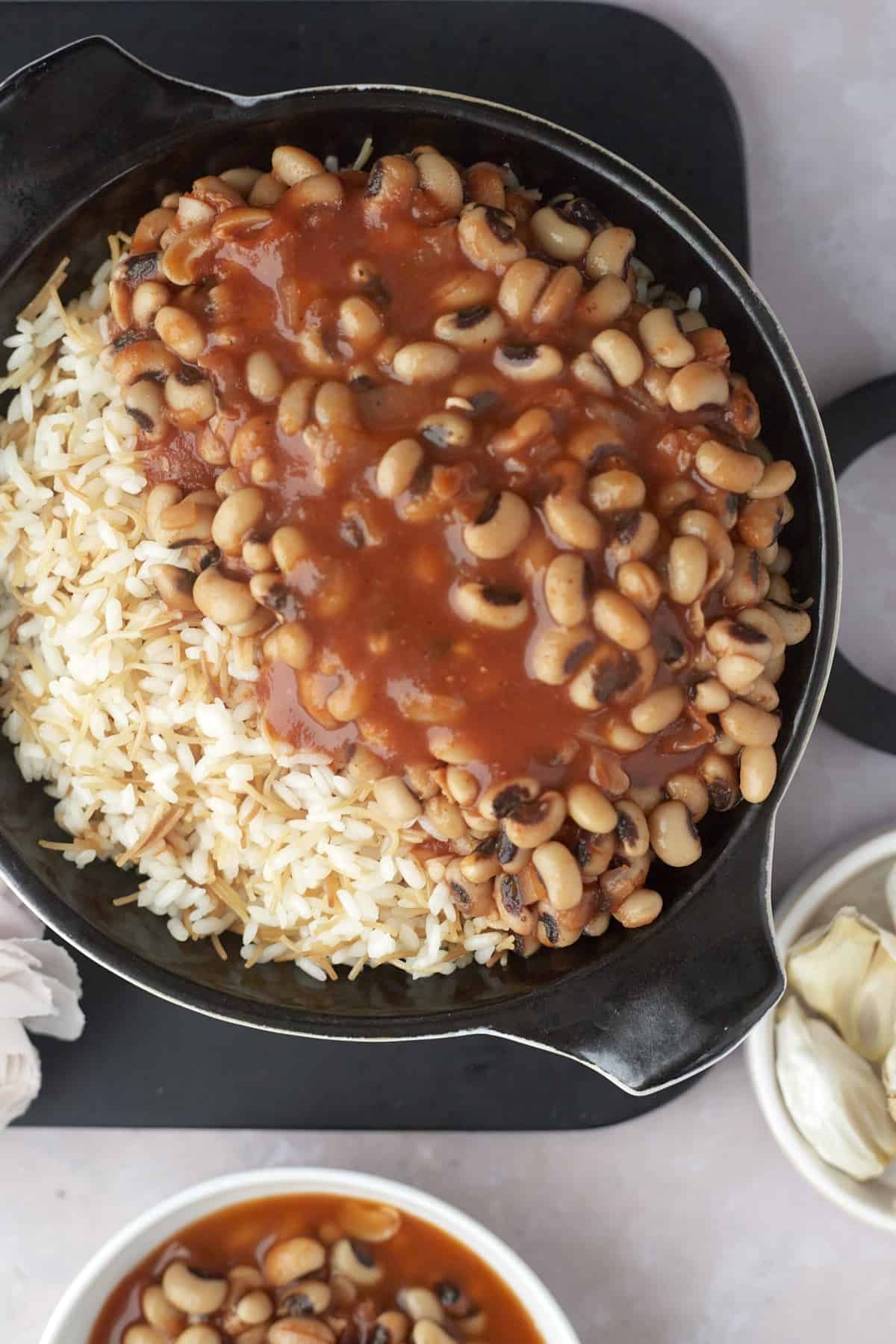 overhead image of a skillet of vermicelli rice topped with black-eyed pea stew