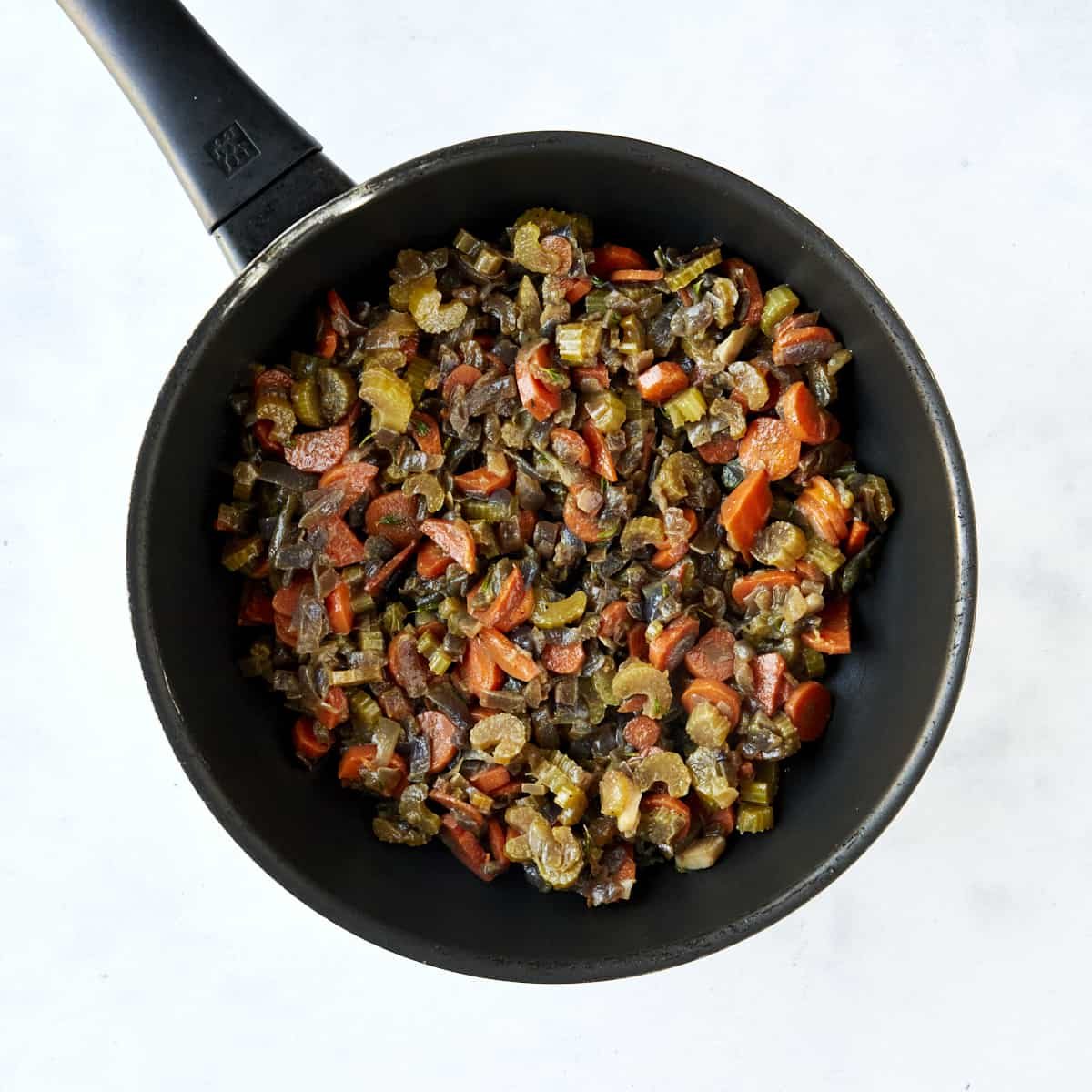 Sautéed veggies in a skillet and a mixing bowl full of Mediterranean-style dressing ingredients.