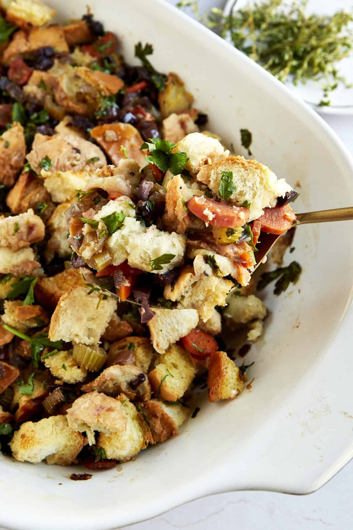 A spoon scooping up a bite of bread stuffing from a baking dish.
