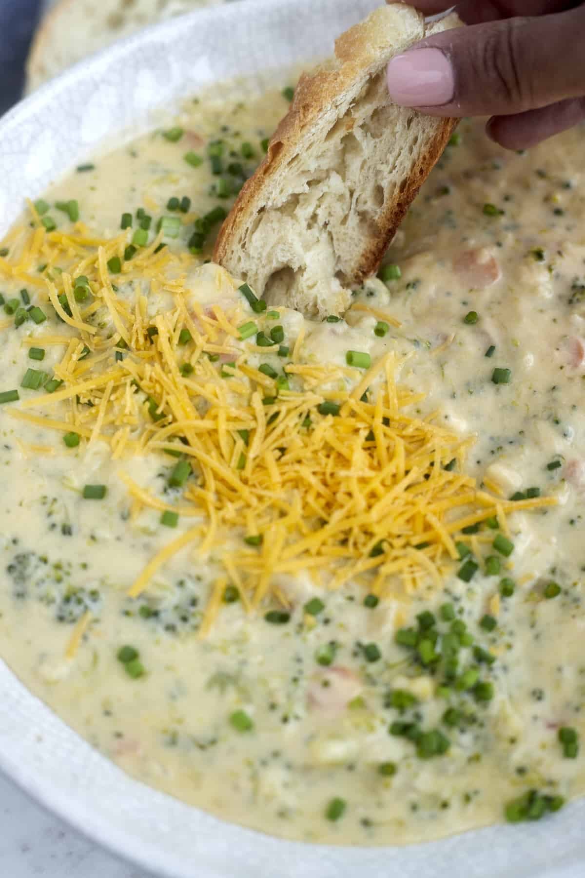 bread being dipped into broccoli & cheese soup.