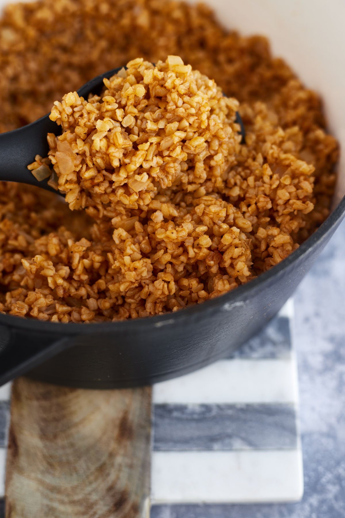 a spoonful of bulgur pilaf being lifted from a pot