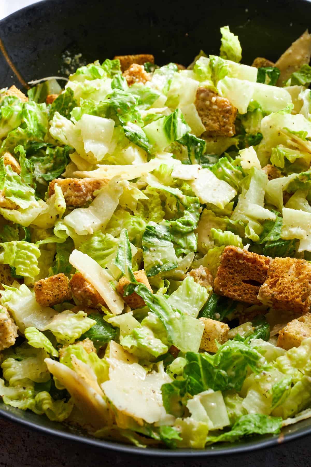 Close up image of a Caesar salad tossed with dressing.