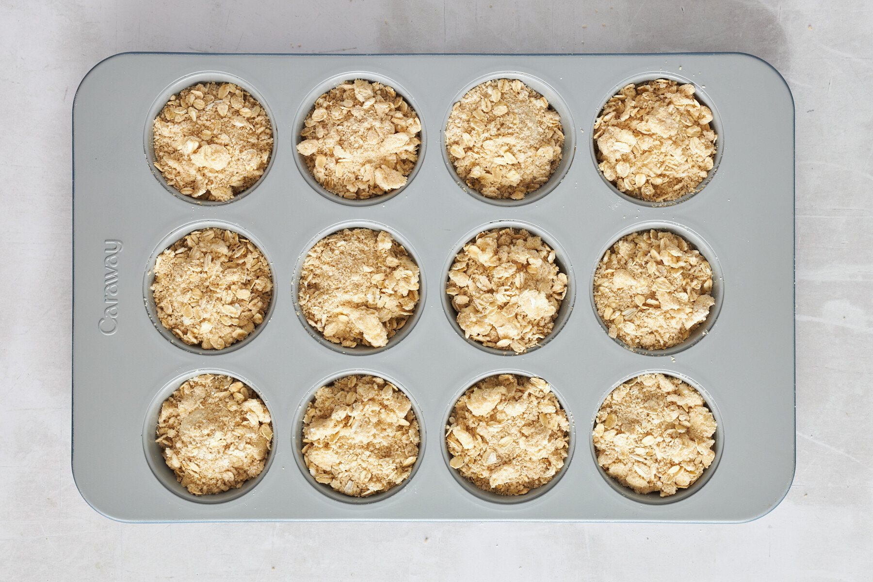 Rhodes dinner rolls in a muffin tin topped with an oat crumble.